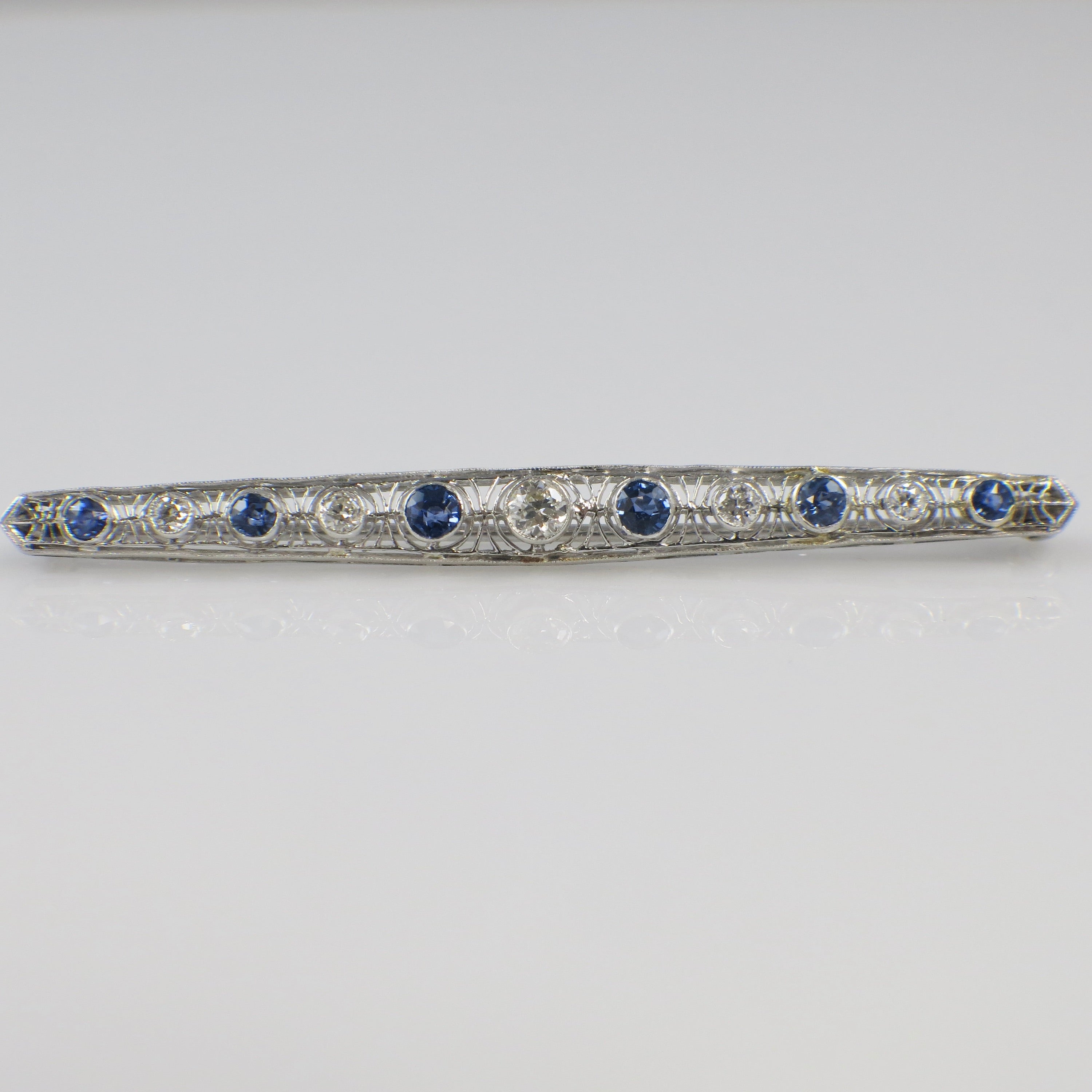 Art Deco 14K white gold diamond and sapphire pin featuring a bee design, with intricate detailing and sparkling gemstones.