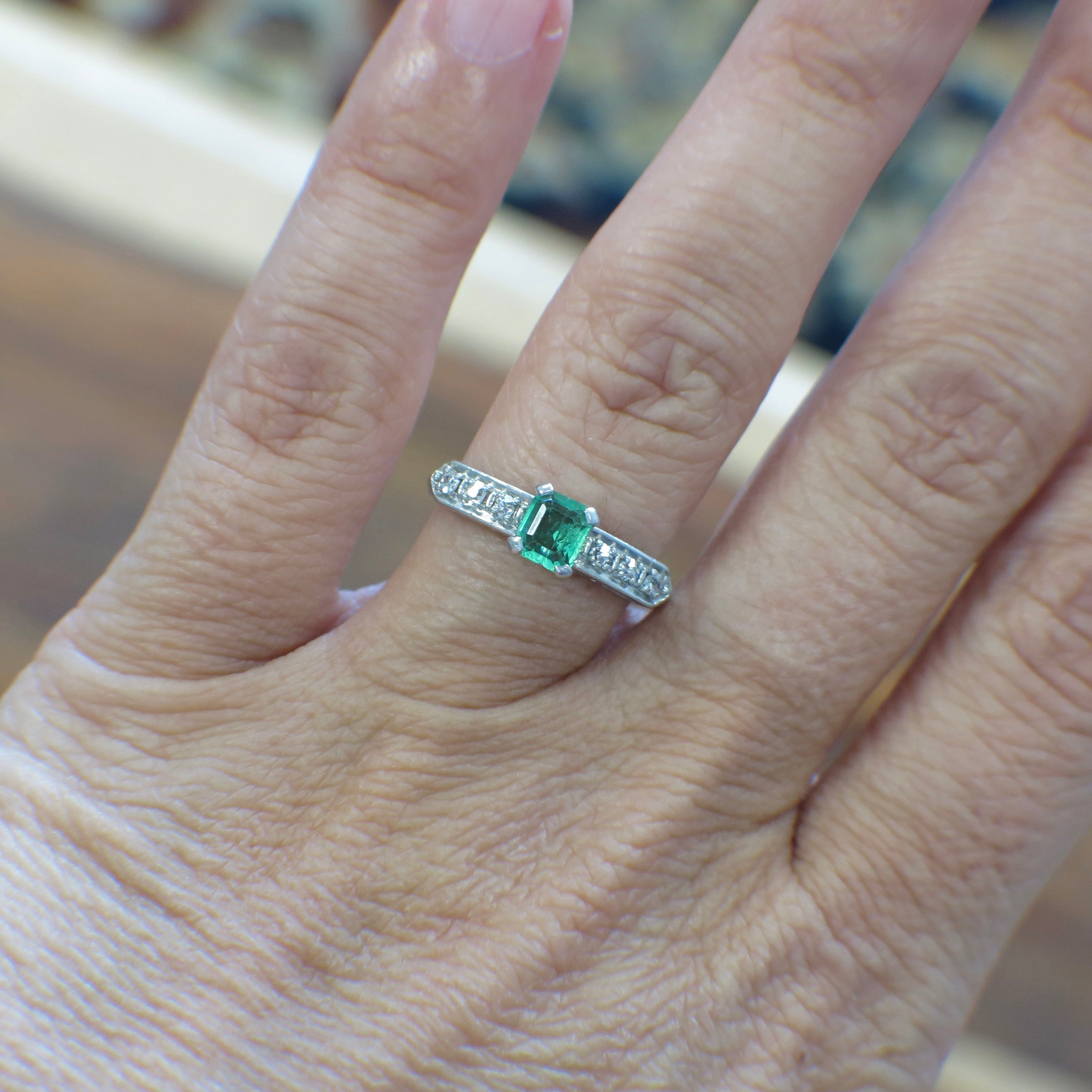 Vintage Art Deco emerald ring with platinum band and diamond accents, circa 1930s, showcasing intricate design and elegant craftsmanship.