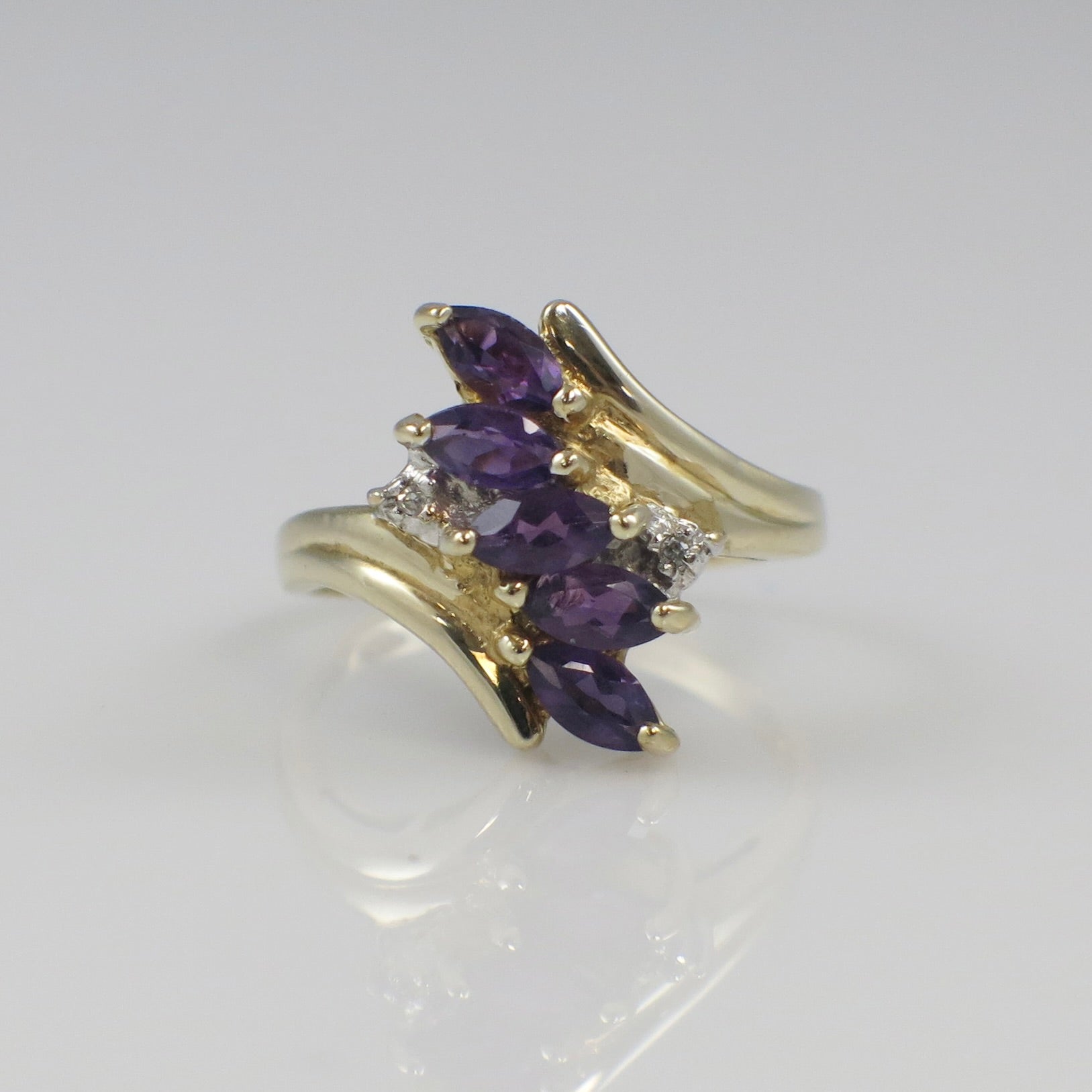 10K yellow gold amethyst marquise cluster ring with diamond accents, featuring a vibrant purple gemstone and sparkling side stones.