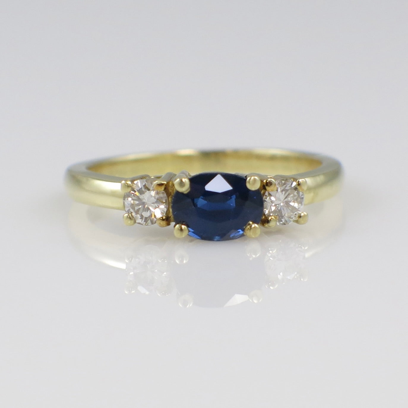 Vintage 18K gold East West sapphire and diamond three-stone ring with intricate detailing and an elegant design.