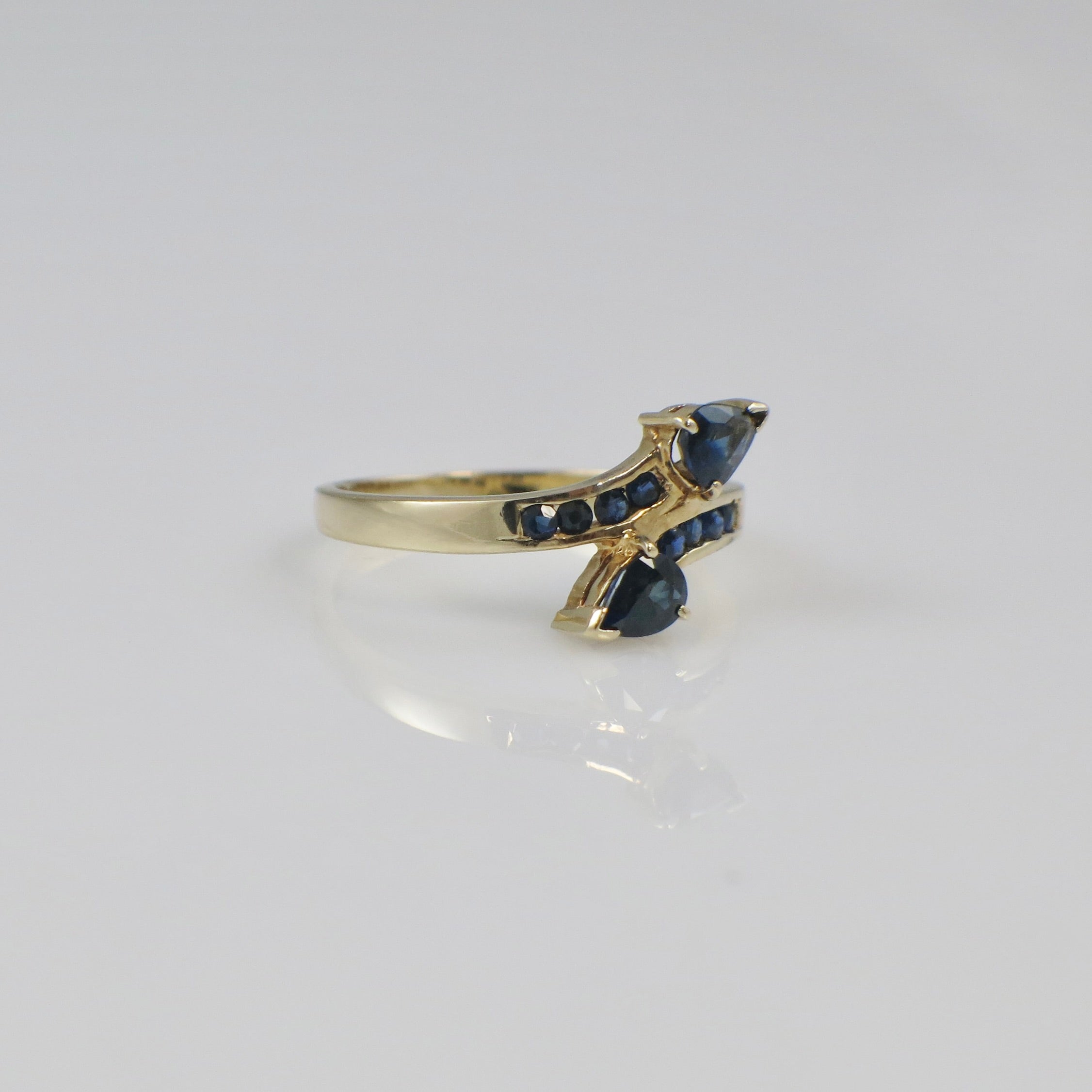 Vintage 14K yellow gold sapphire pear bypass ring with elegant design, featuring a blue sapphire gemstone and intricate detailing.
