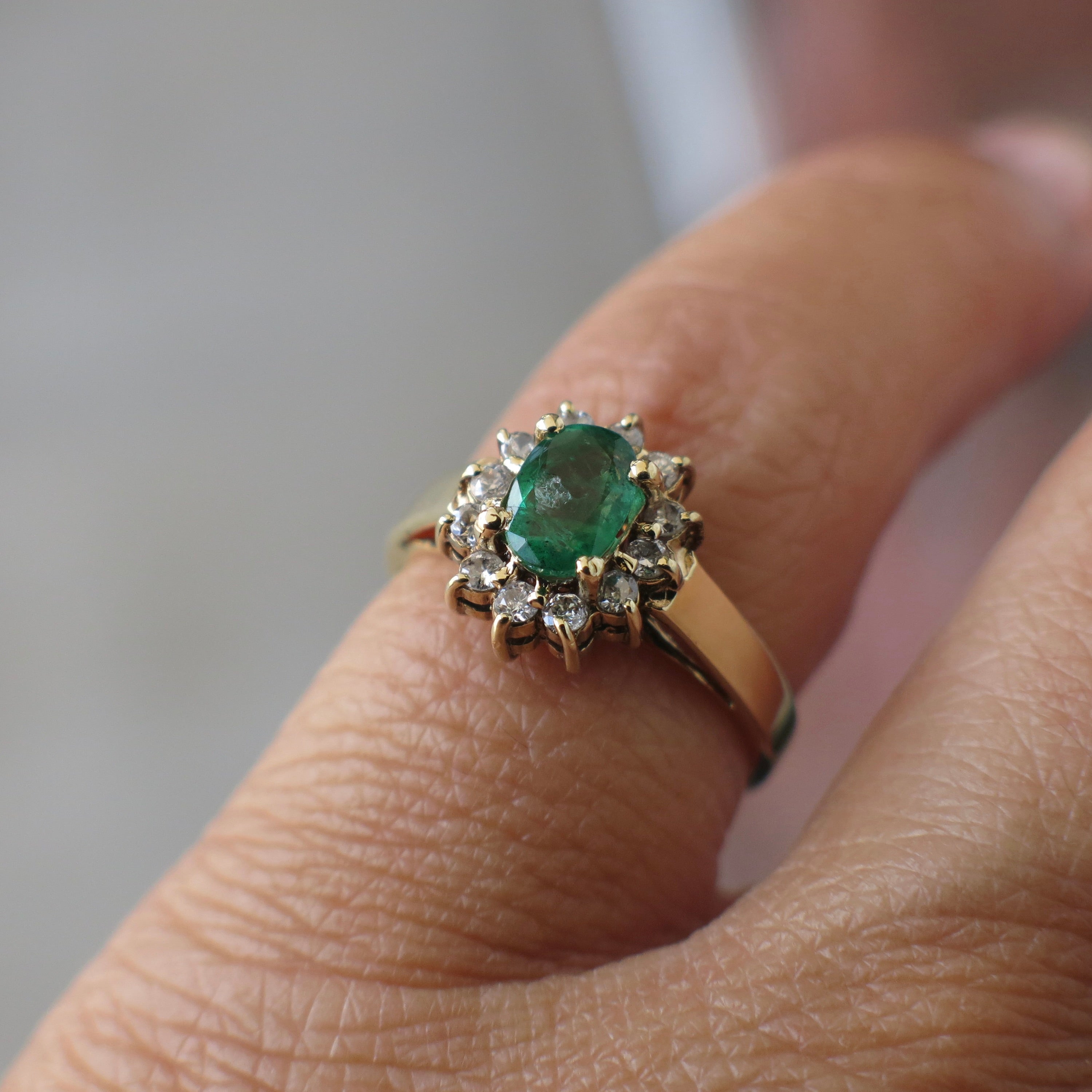 Vintage 14K yellow gold emerald and diamond halo ring with intricate detailing, crafted by Black Market LLC.