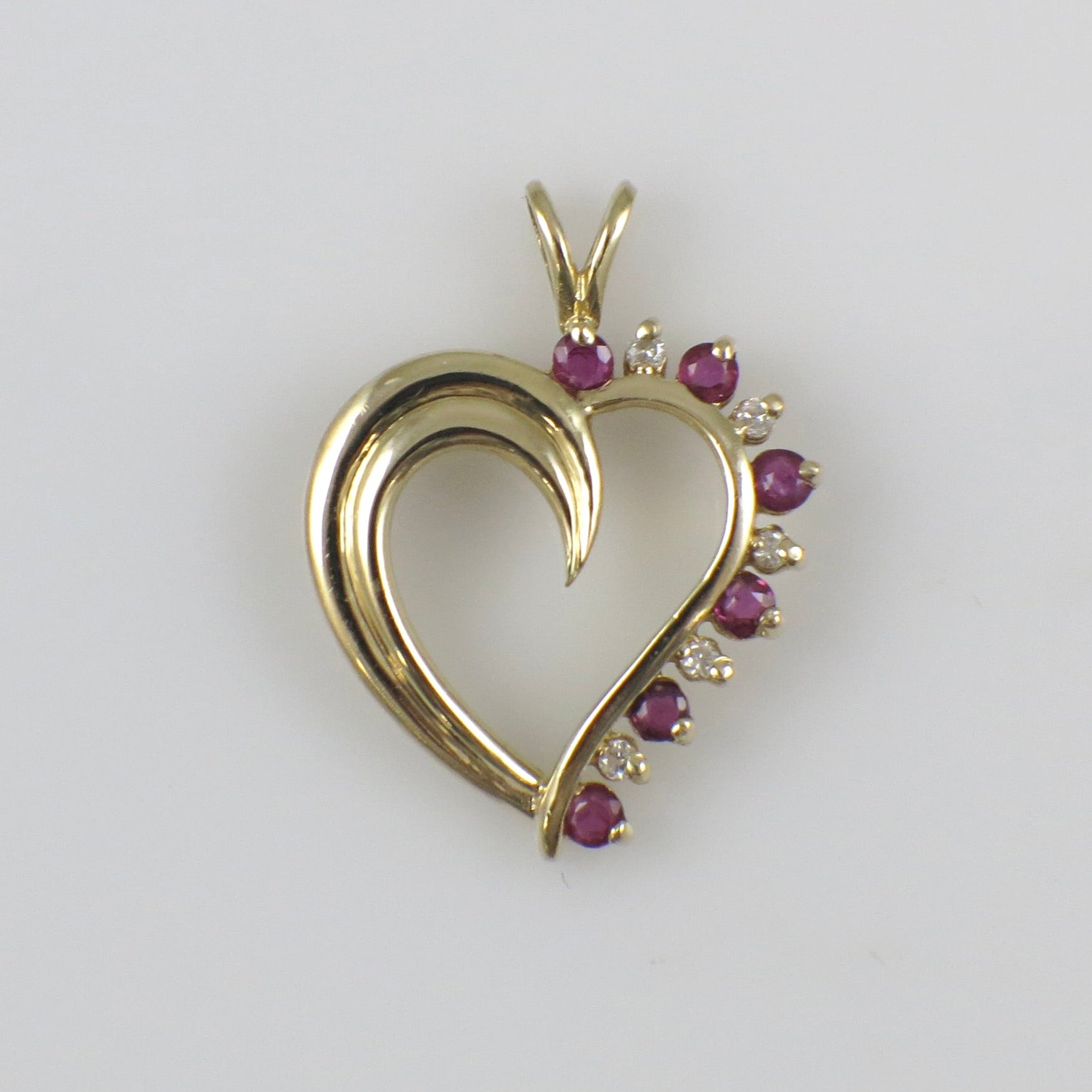 Vintage 14K yellow gold ruby and diamond heart pendant necklace with intricate detailing and a delicate chain.