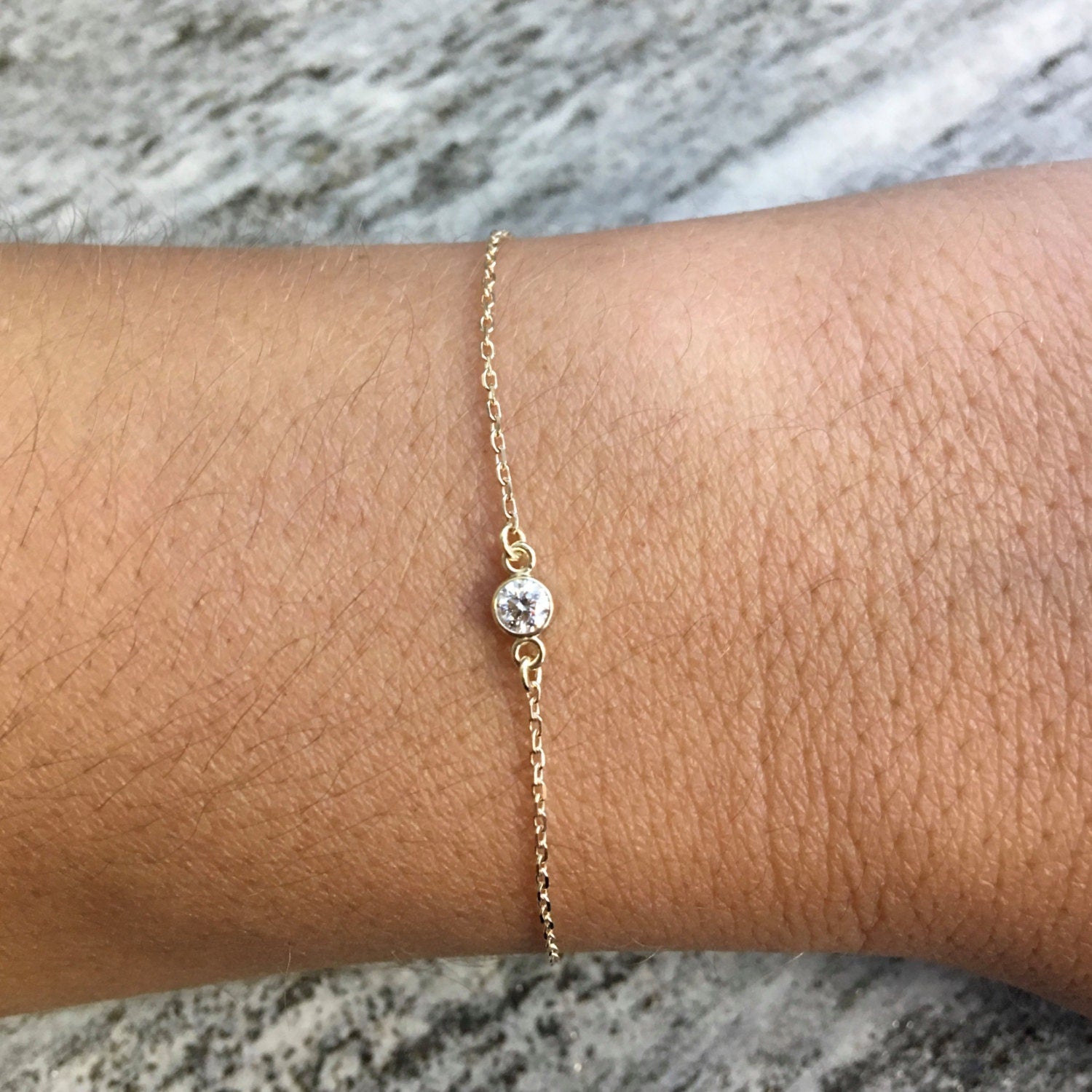 14K gold diamond bezel bracelet by Black Market LLC featuring dainty layering style with 0.10 CT diamonds on a yellow gold band.