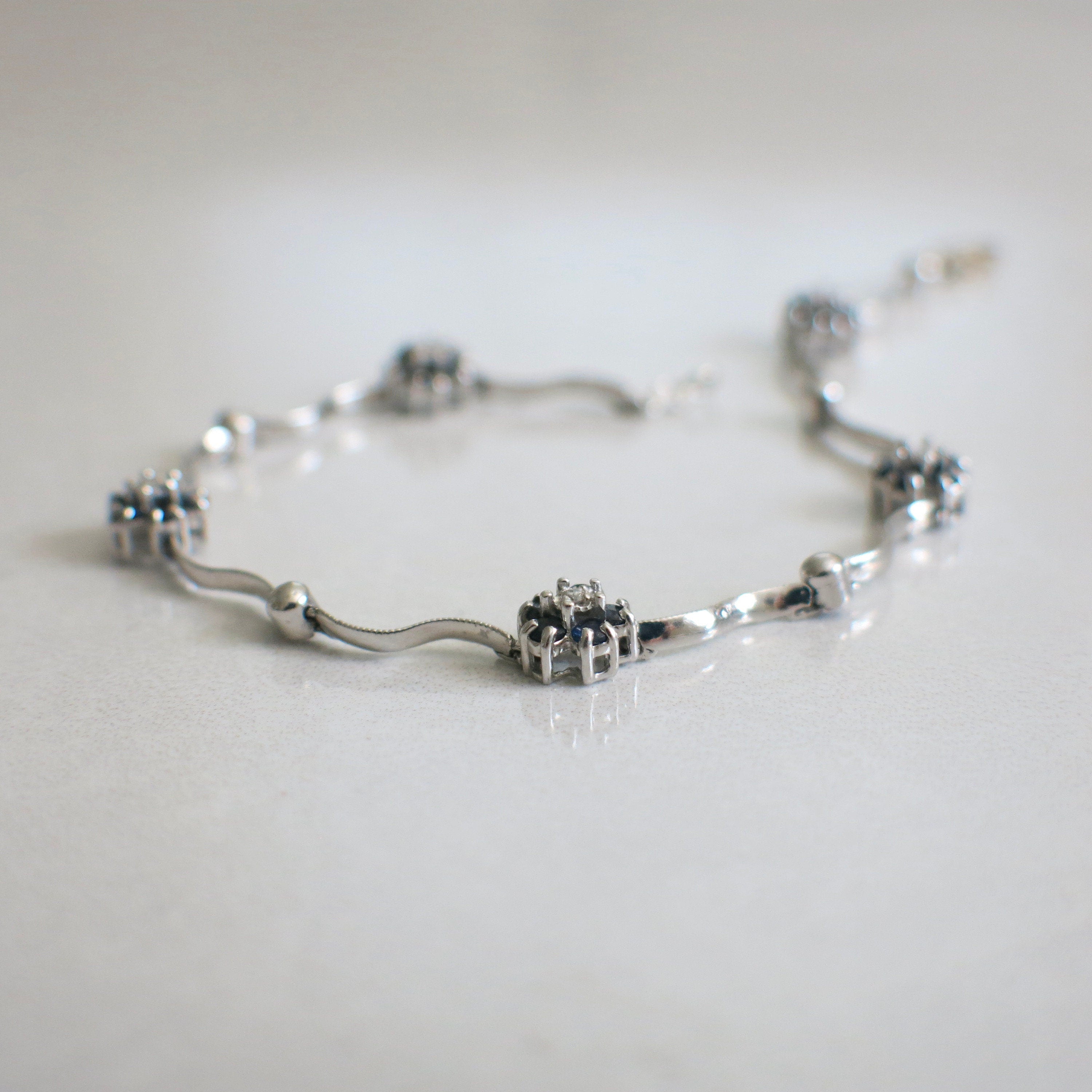 14K white gold sapphire and diamond floral bracelet, 7-inch delicate design featuring intricate flower motifs.