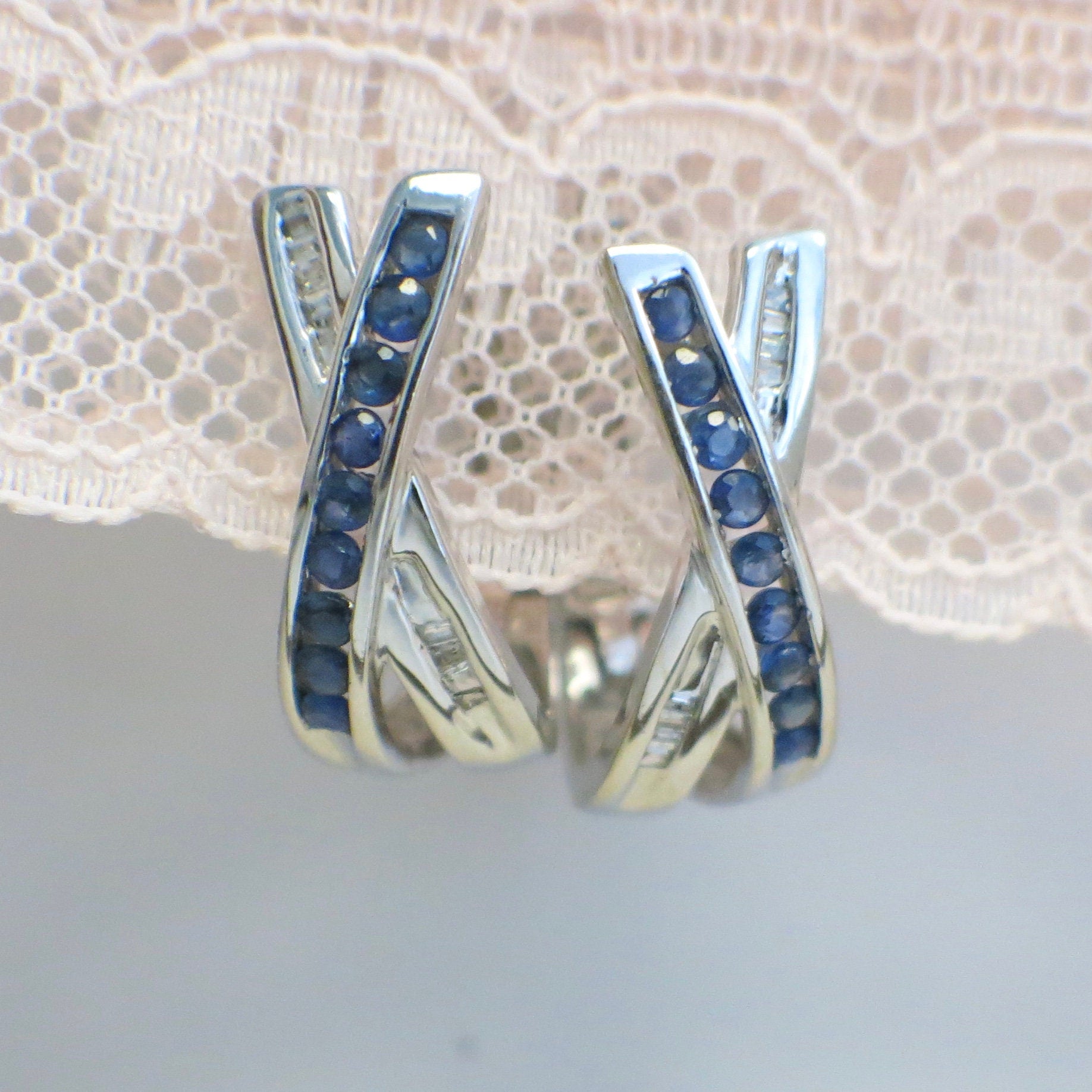 14K white gold sapphire and diamond hoop earrings with princess cut sapphires and baguette diamonds, featuring an X design.