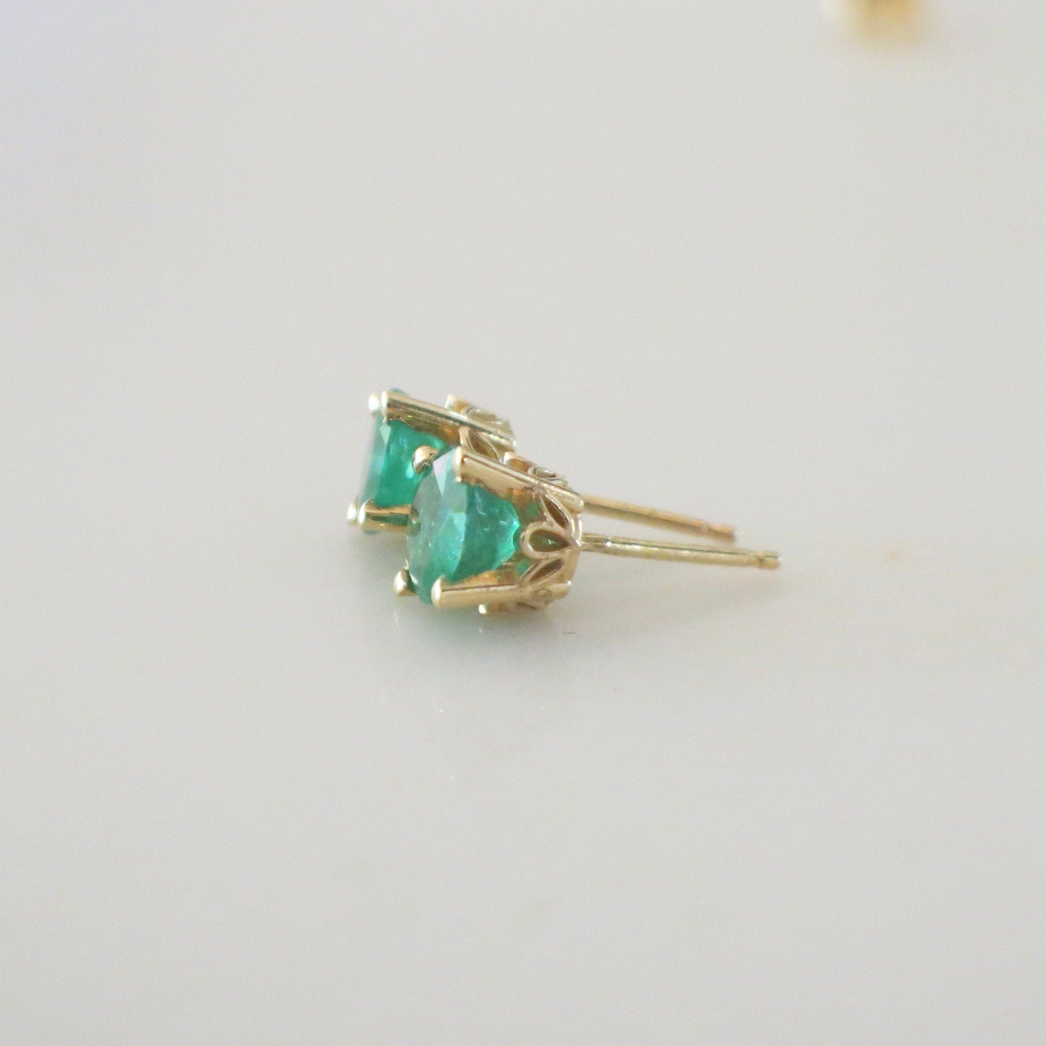 14K yellow gold emerald stud earrings with 1.5 carats of green gemstones in a basket setting, by Black Market LLC.