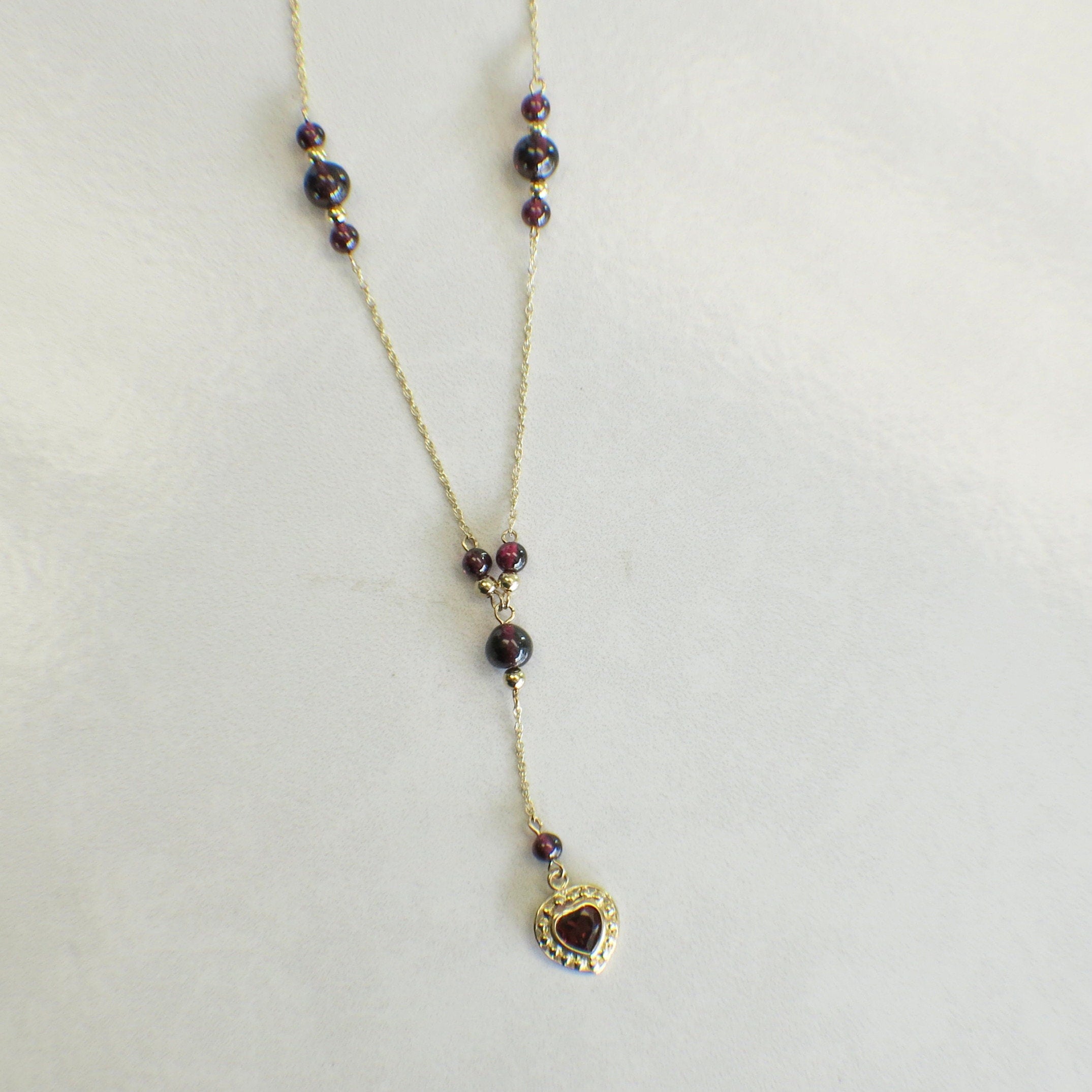 14K gold garnet bead drop necklace with heart charm and rhodolite garnet dangle, featuring elegant gold chain and vibrant red gemstones.