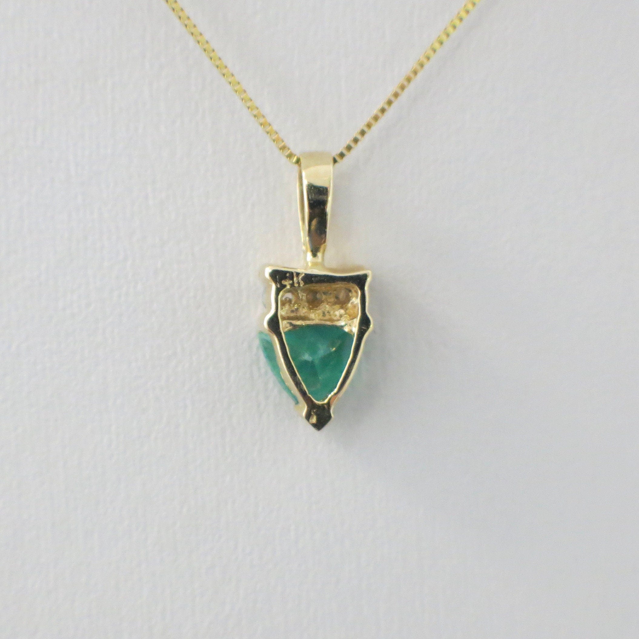 14K yellow gold necklace with a trillion emerald and diamond pendant on a box chain, by Black Market LLC.