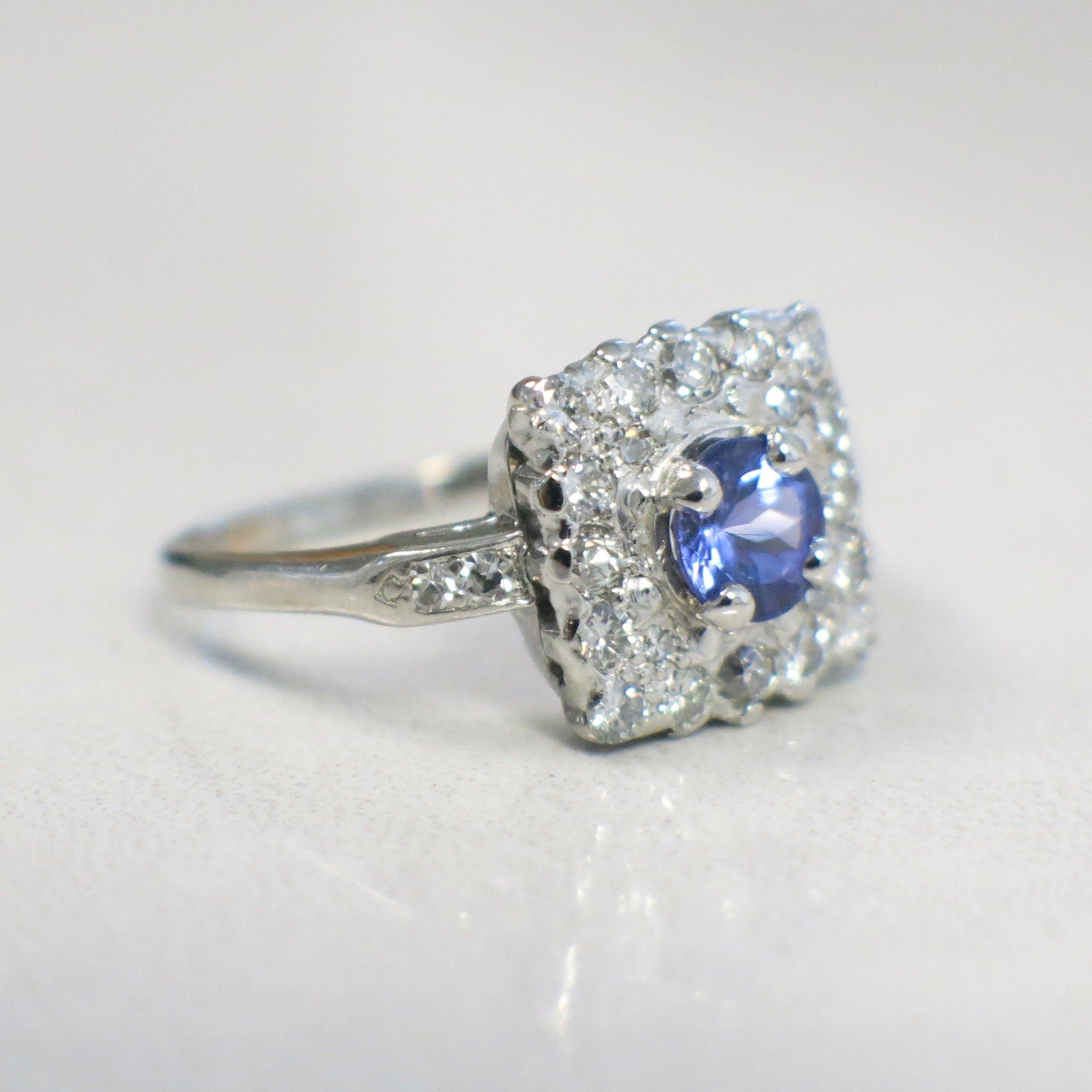 Vintage platinum tanzanite and diamond halo ring featuring a square cluster design with .56 CTW diamonds, size 6.75.