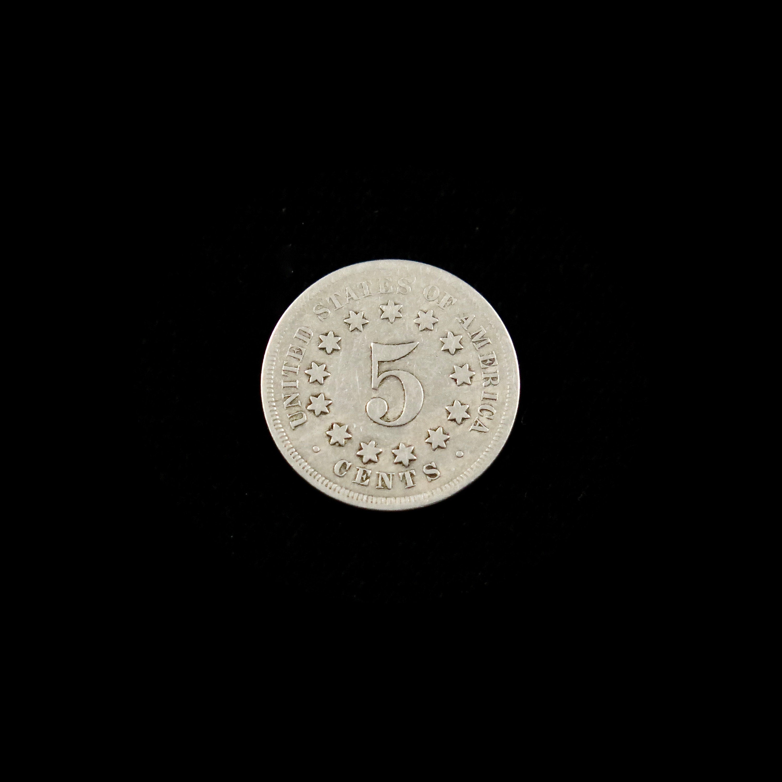1867 Shield Nickel coin from Black Market LLC showing the no rays reverse side with a good condition raw U.S. five-cent nickel.