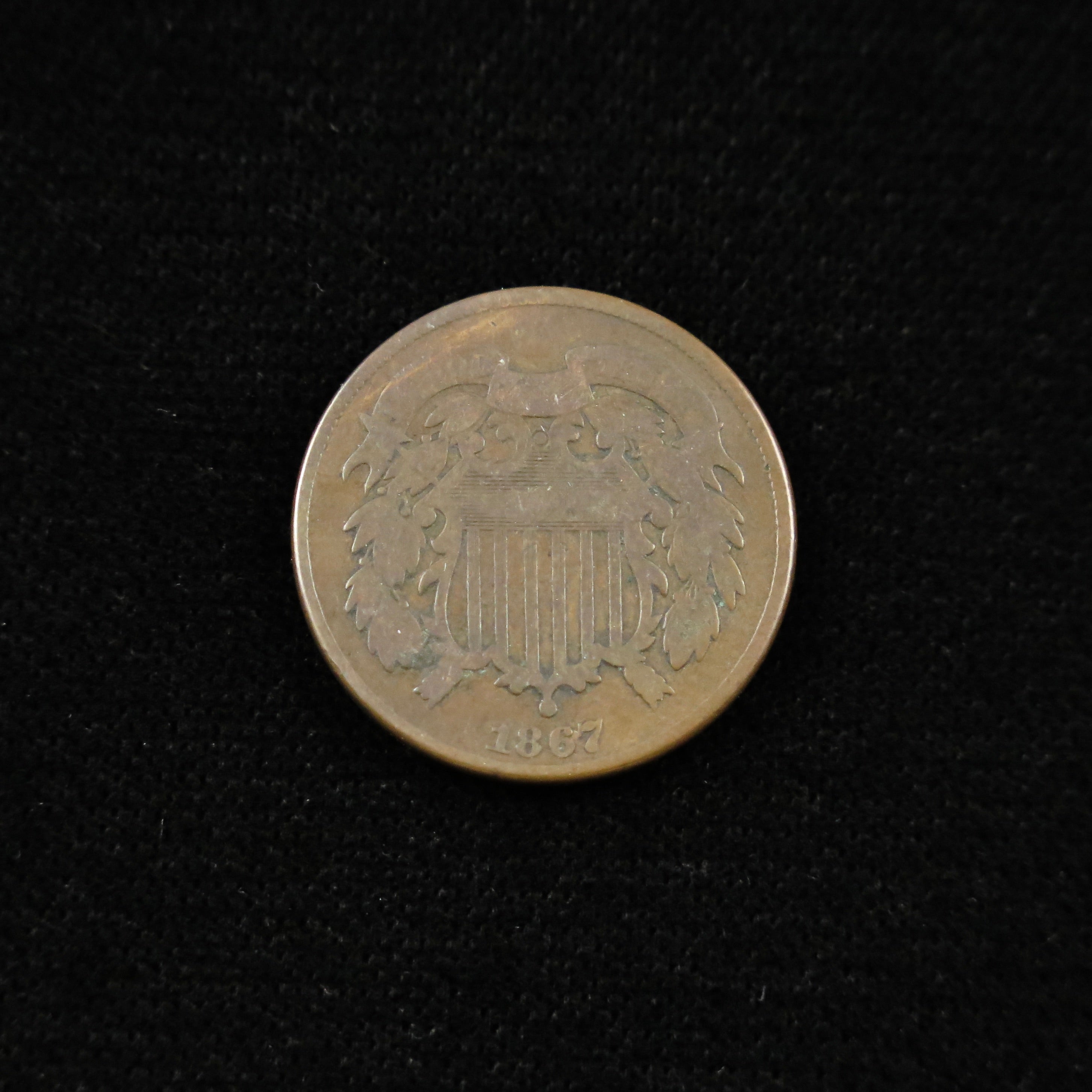 Raw 1867 Two Cent U.S. copper coin from Black Market LLC, historic Civil War era issue with detailed obverse design.