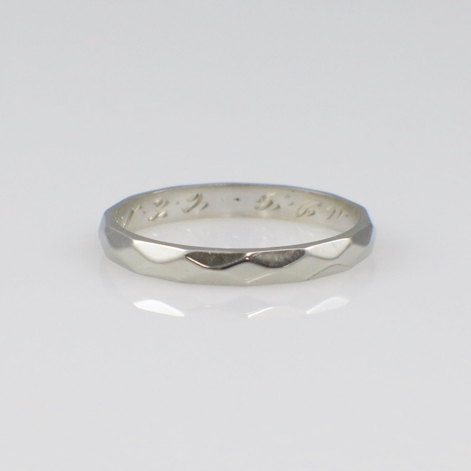 Silver ring with engraved text on a light gray background