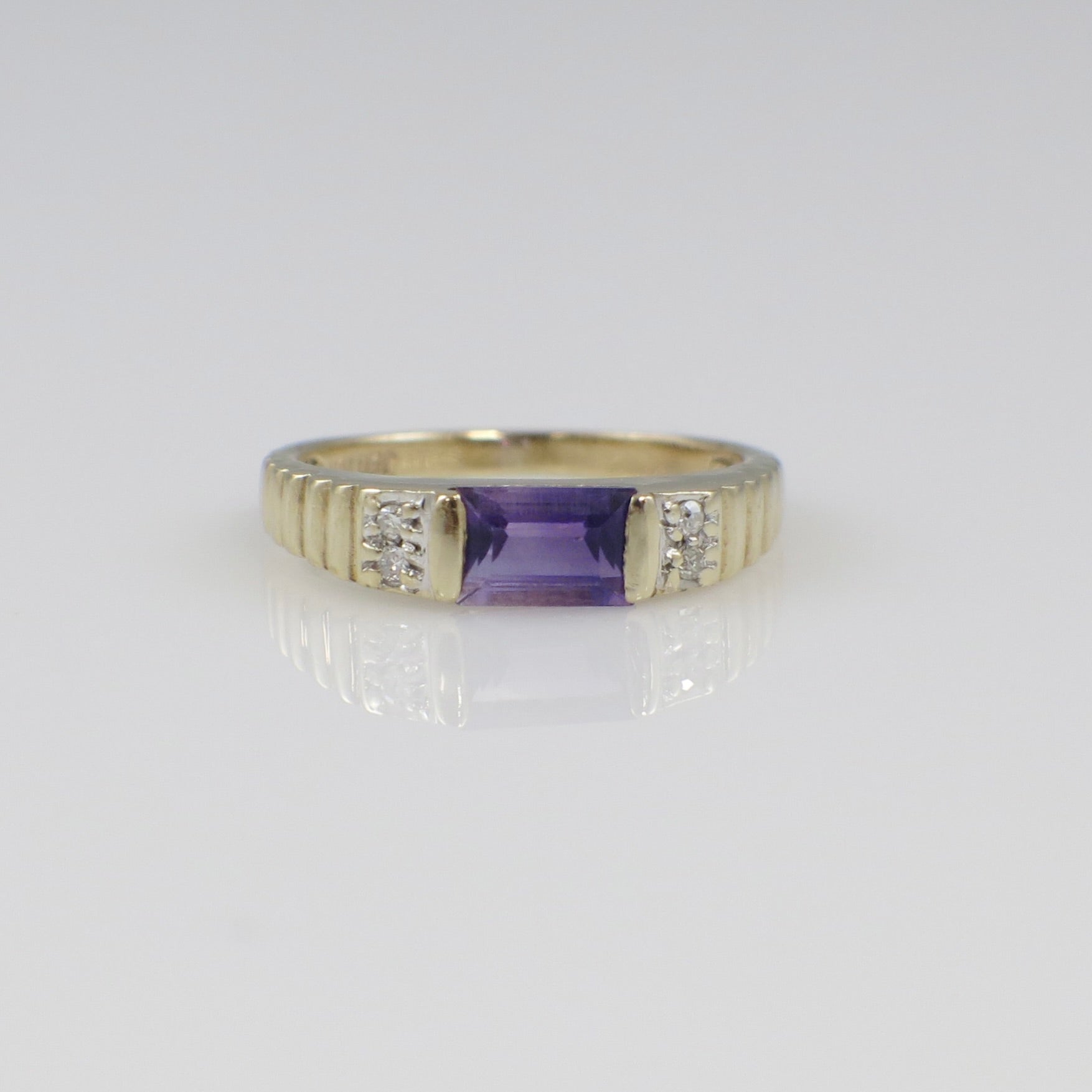 Yellow gold amethyst ring with emerald cut gemstone and diamond accents, showcasing a stylish jewelry piece from Black Market LLC.