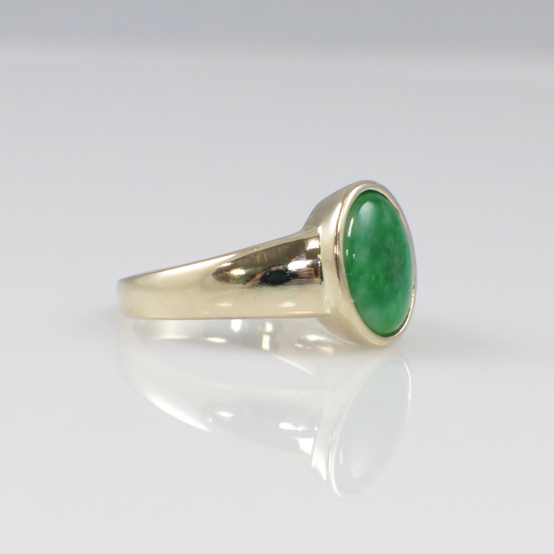 14K yellow gold jade ring with oval cabochon bezel set, size 6.75, featuring a smooth, polished green jade gemstone.