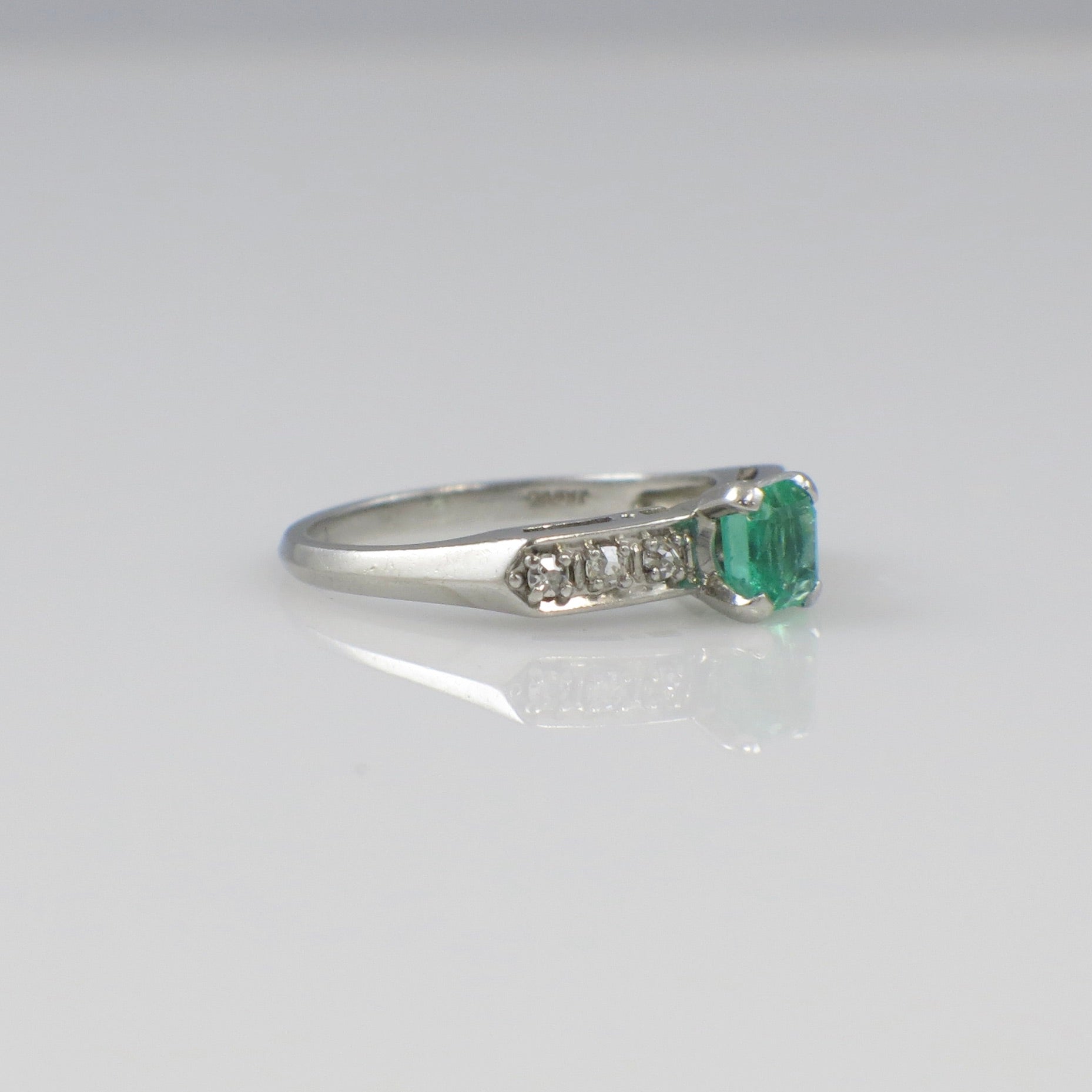 Vintage Art Deco emerald ring with platinum band and diamond accents, circa 1930s, from Black Market LLC.