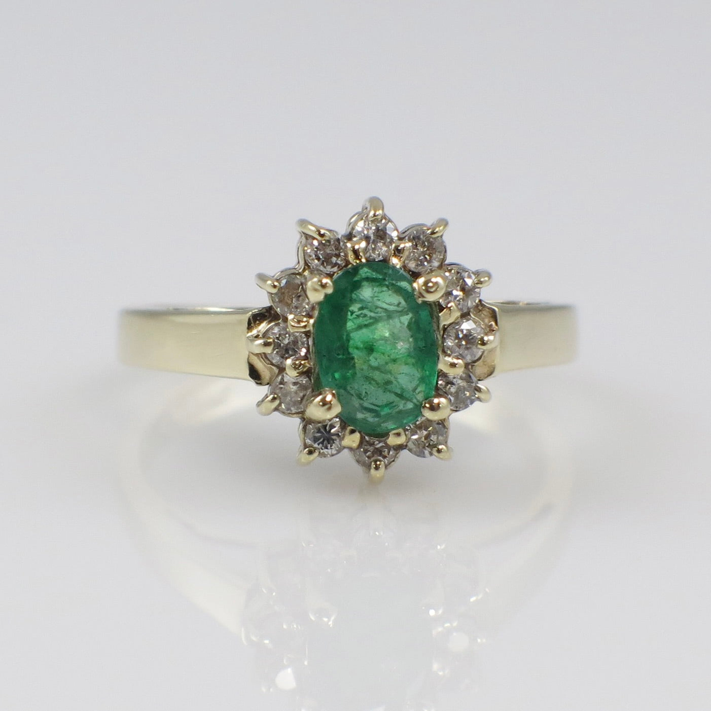 Vintage 14K yellow gold emerald and diamond halo ring featuring a natural green emerald centerpiece and sparkling diamond accents.