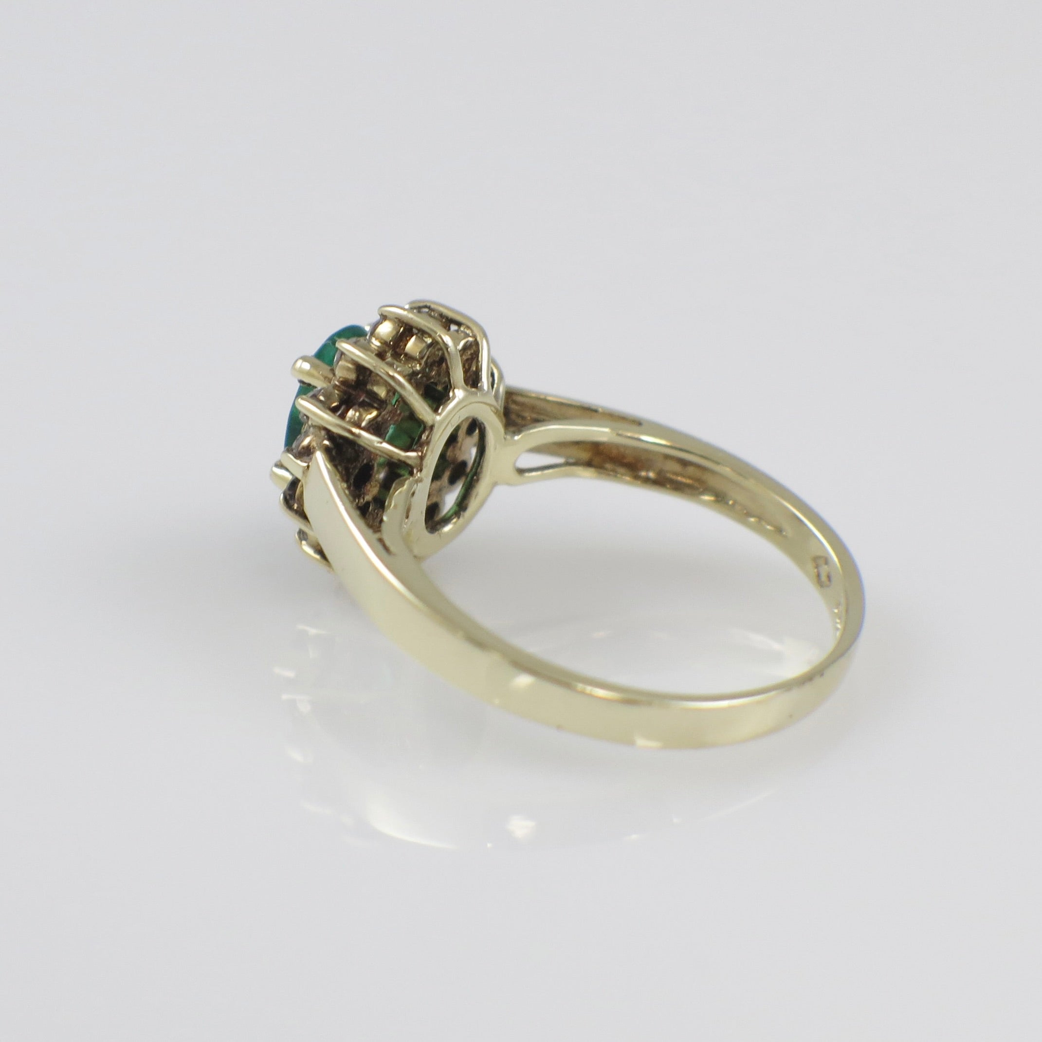Vintage 14K yellow gold ring featuring a natural emerald center stone with a diamond halo setting.