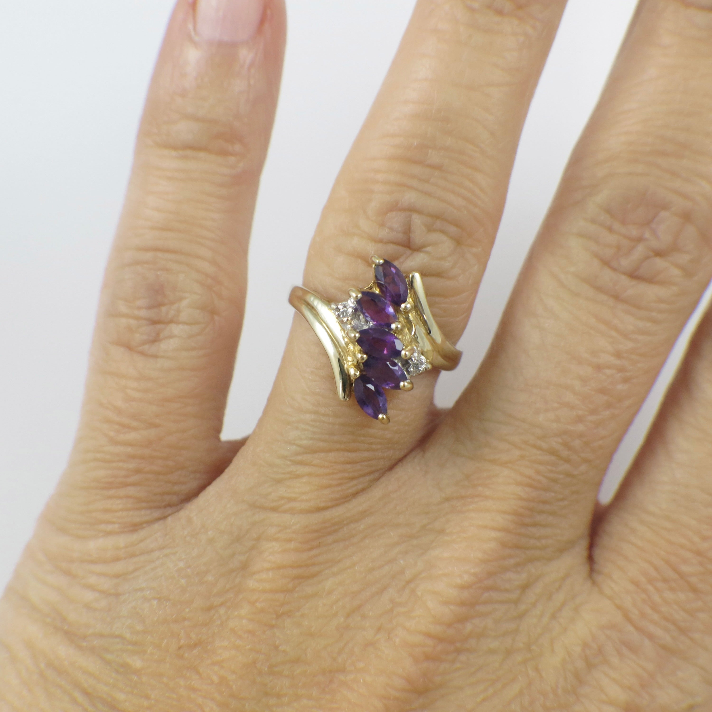 Yellow gold amethyst marquise cluster ring with diamond accents, featuring intricate design and sparkling gemstones.