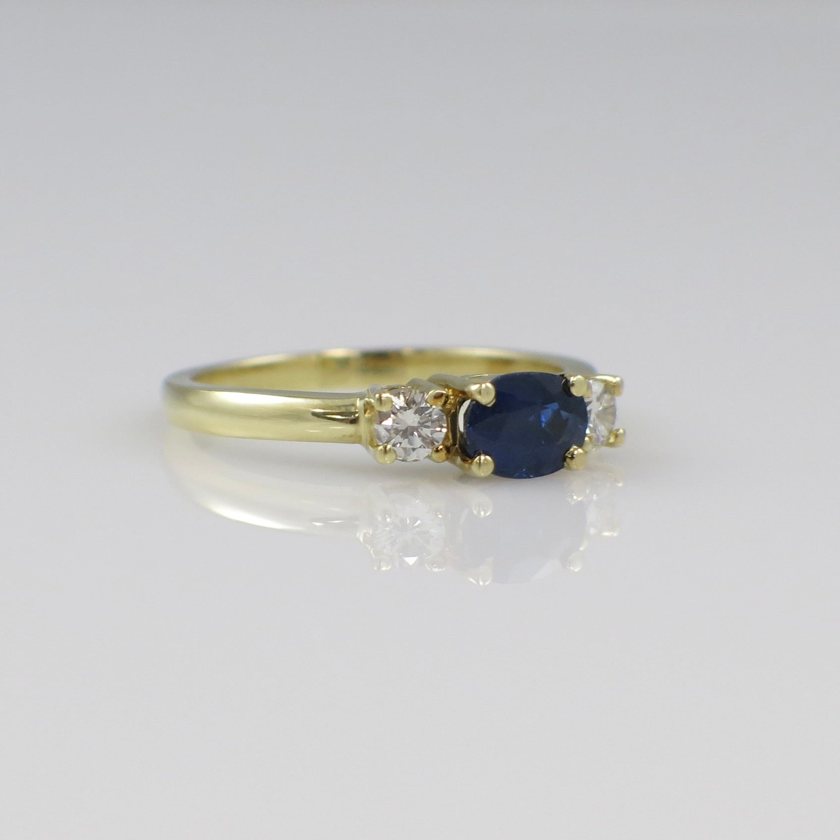 Vintage 18K gold East West sapphire and diamond three-stone ring featuring a classic design with elegant gemstones.