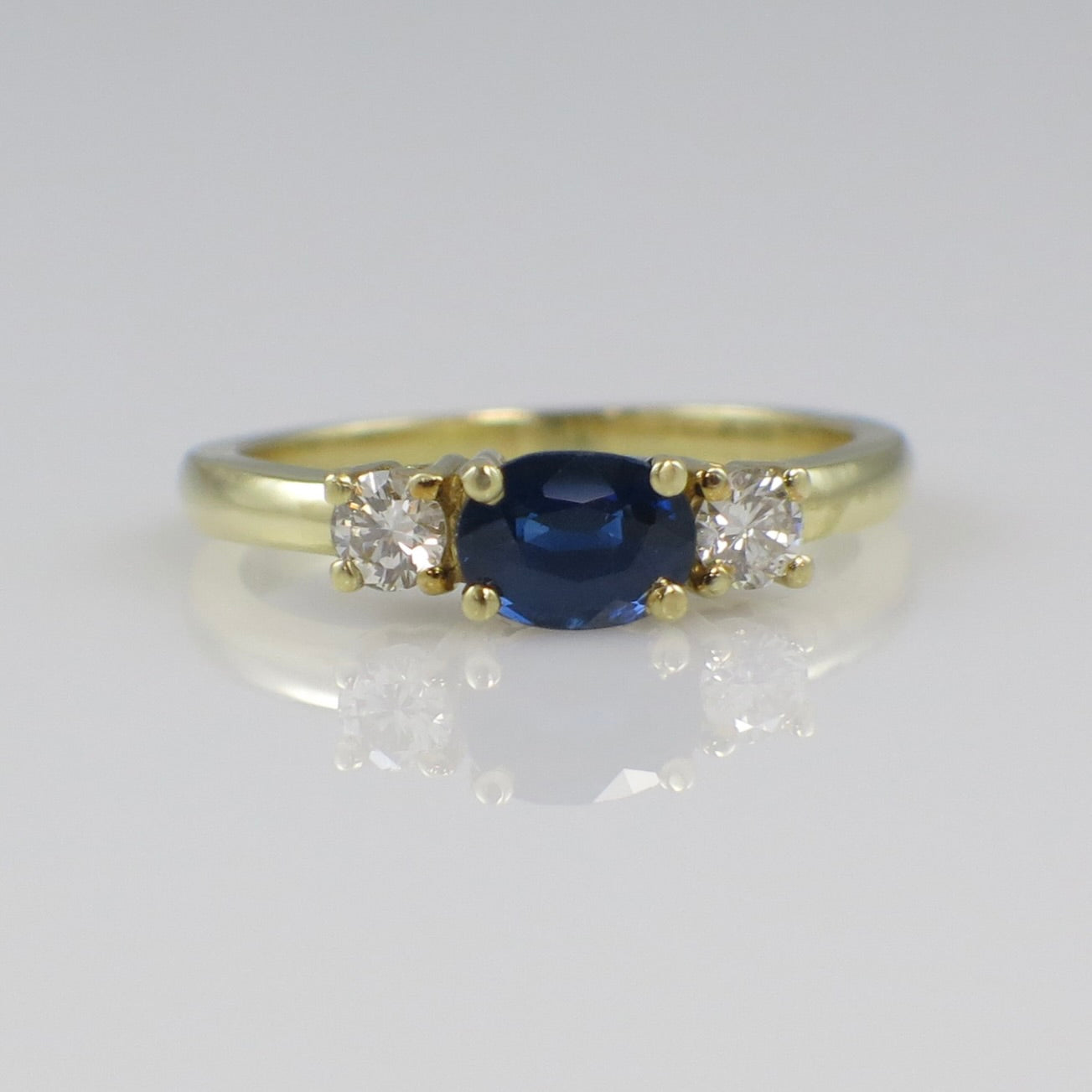 Vintage 18K gold east-west sapphire and diamond three-stone ring with elegant design, featuring a central sapphire flanked by diamonds.