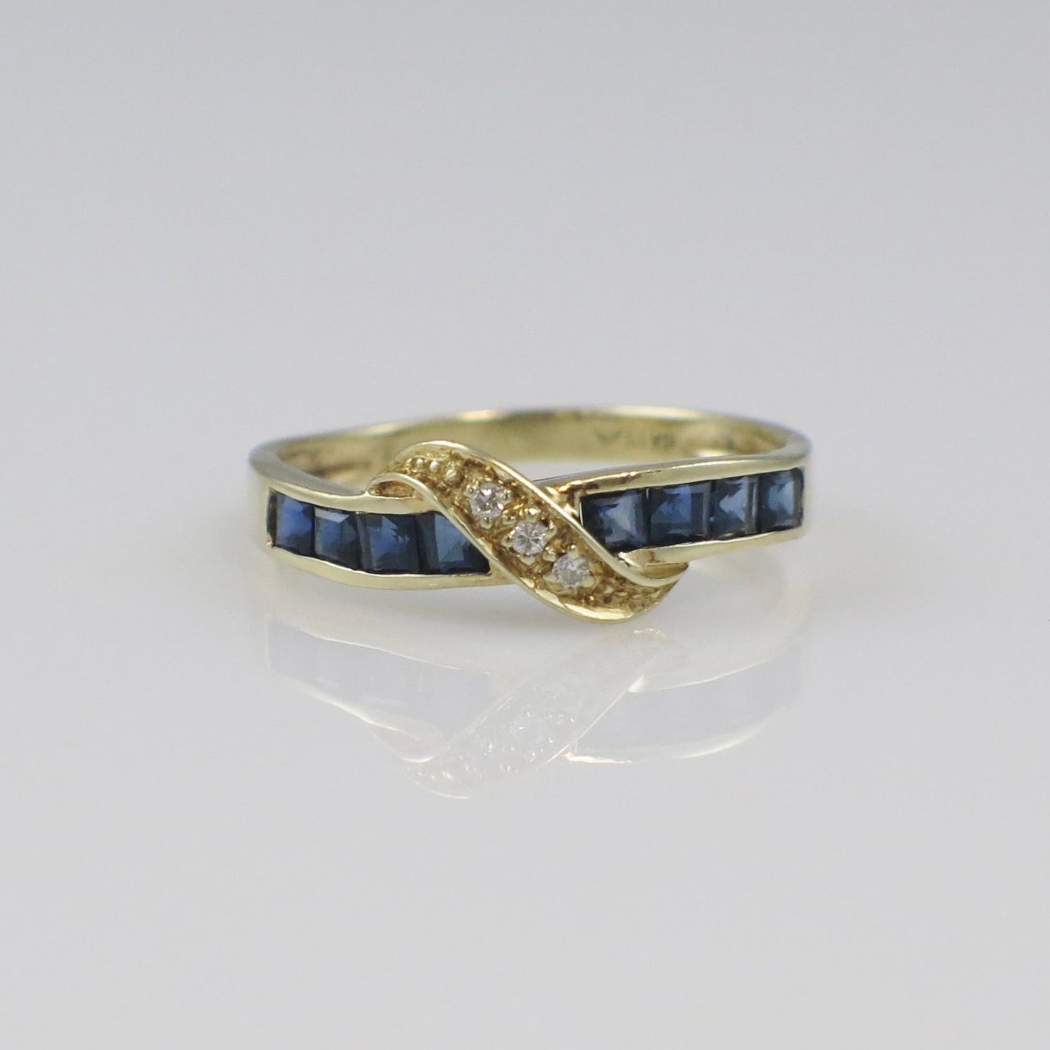 Vintage 14K yellow gold sapphire diamond bypass ring with intricate detailing and a sleek, elegant design.