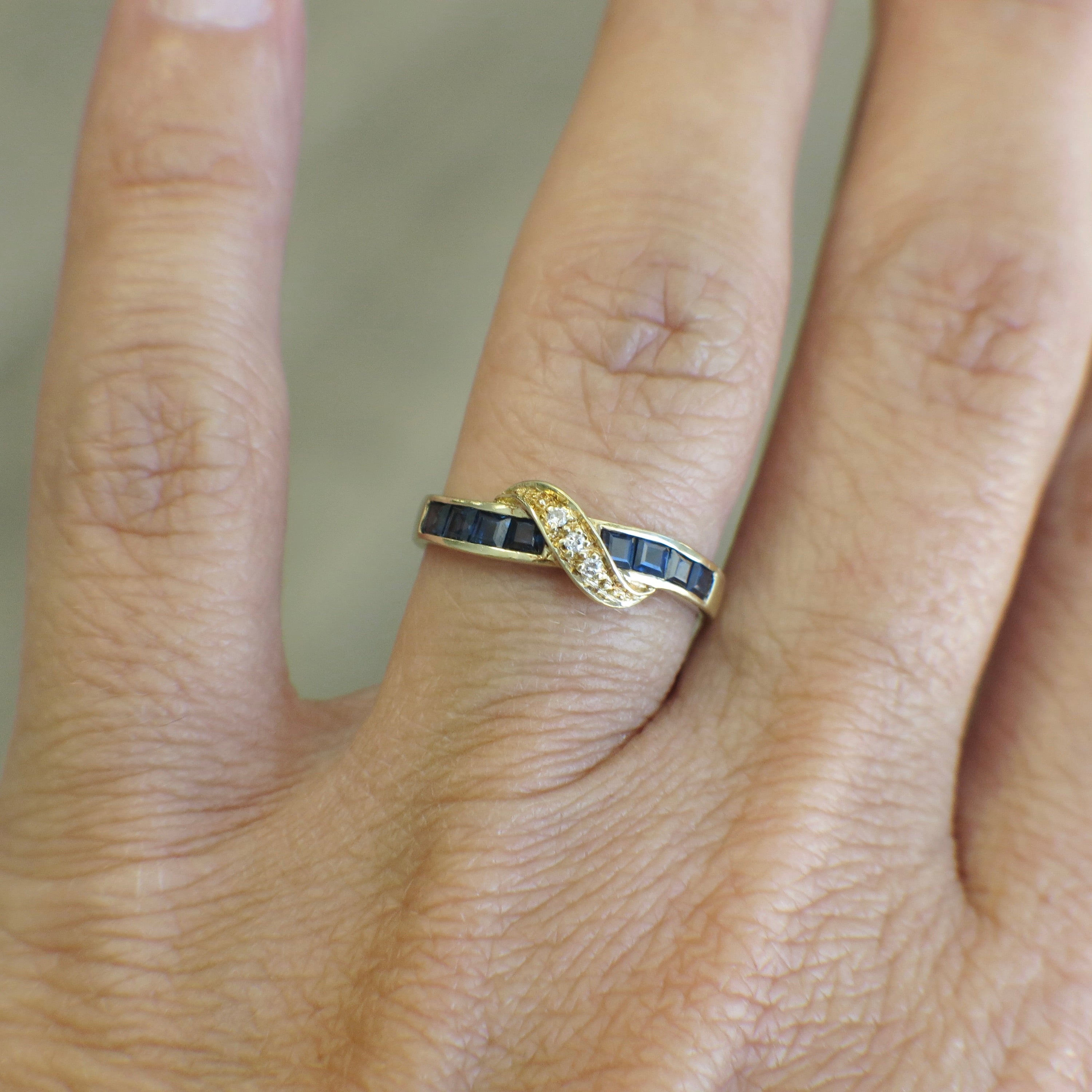 Vintage 14K yellow gold sapphire and diamond bypass ring with black market LLC branding, featuring intricate design and gemstone accents.