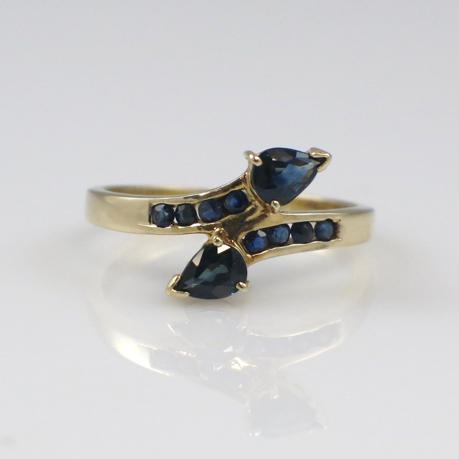 Vintage 14K yellow gold sapphire pear-shaped bypass ring with intricate design, crafted by Black Market LLC.