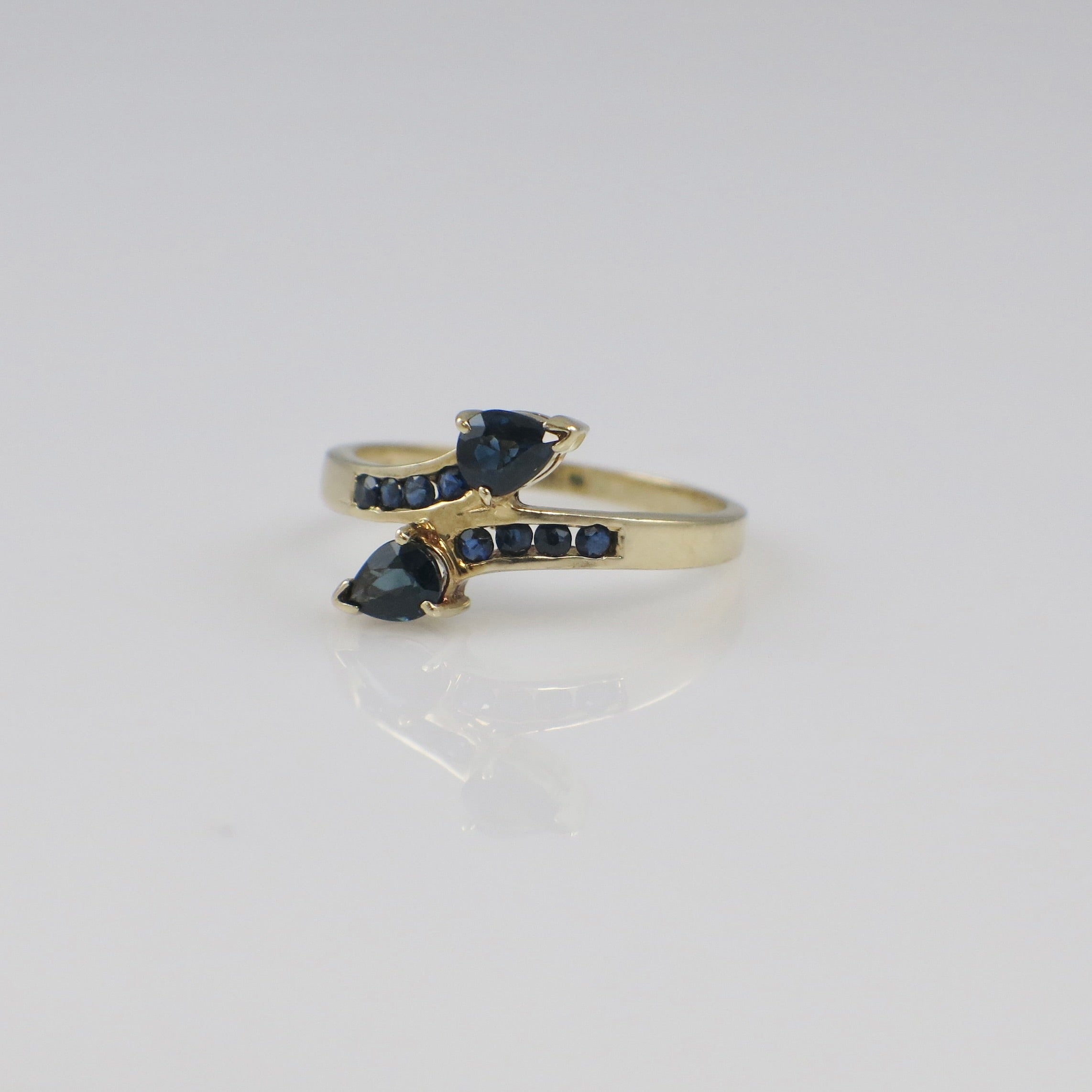 Vintage 14K yellow gold sapphire pear bypass ring with a unique design, featuring a prominent blue sapphire gemstone.
