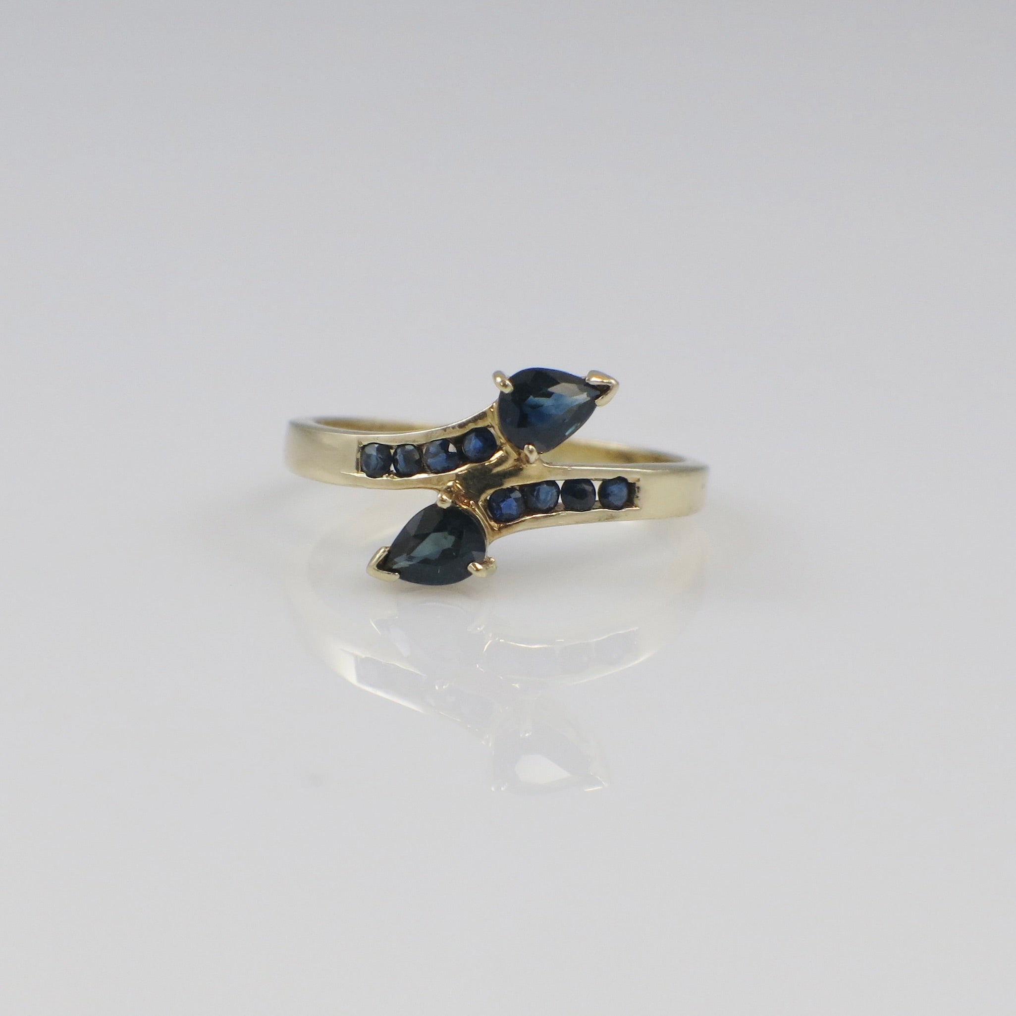 Vintage 14K yellow gold sapphire pear bypass ring with elegant design, featuring a blue gemstone and intricate craftsmanship.