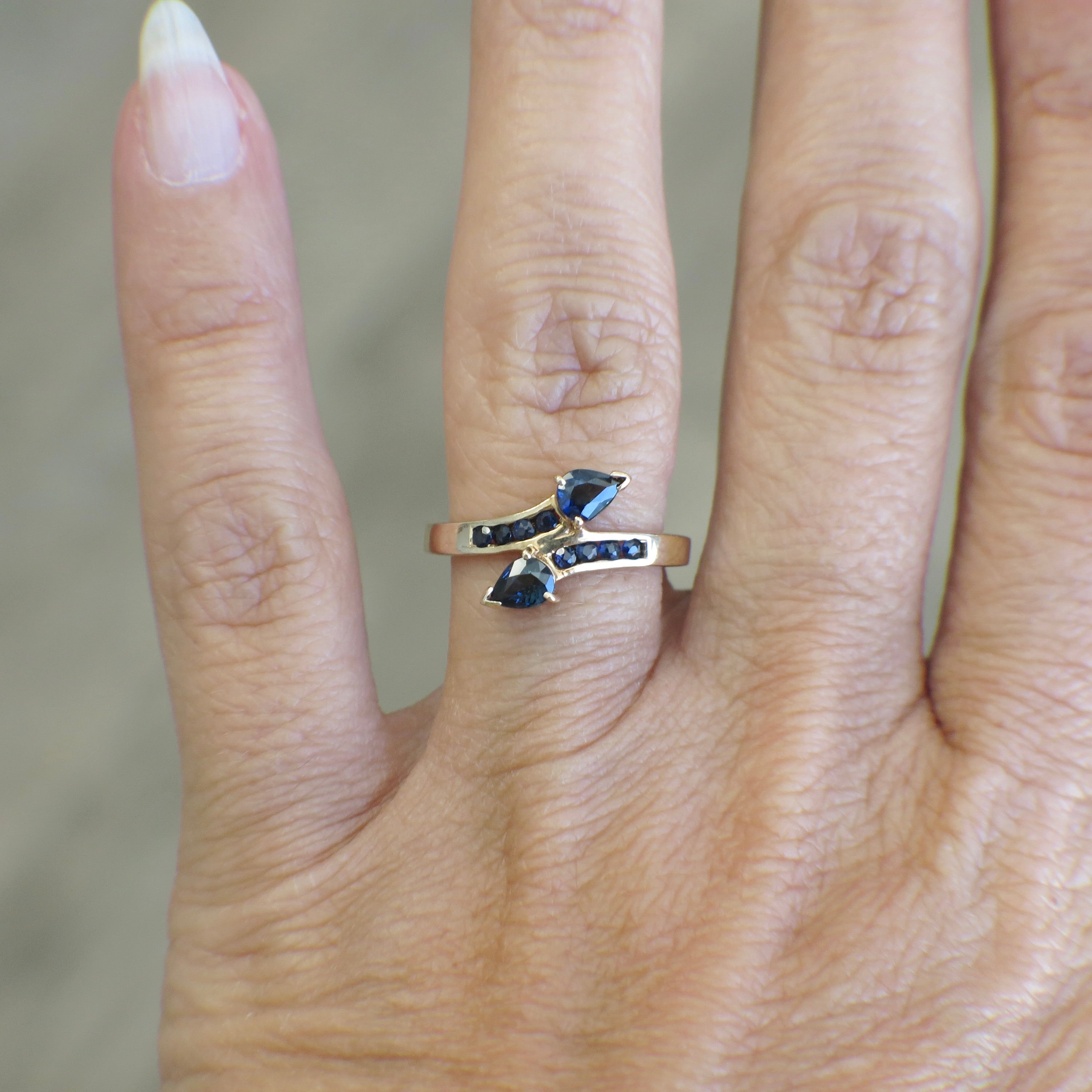 Vintage 14K yellow gold sapphire pear bypass ring with elegant design, featuring a prominent blue sapphire stone.