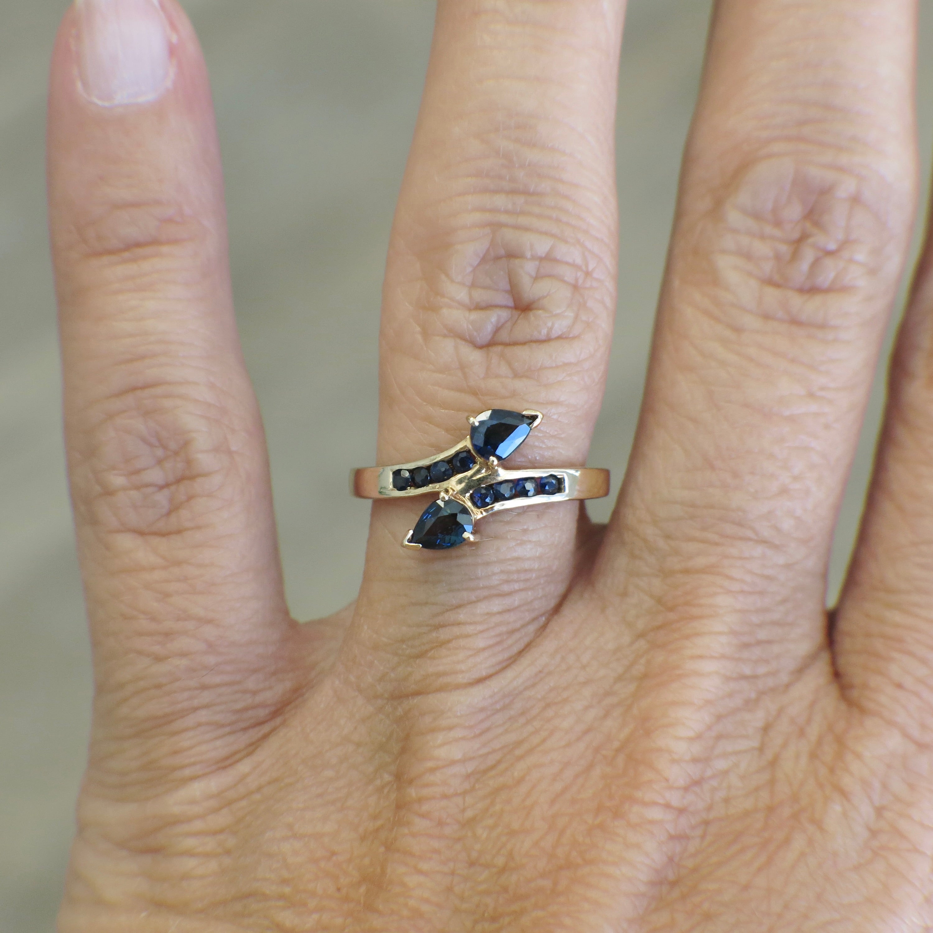 Vintage 14K yellow gold sapphire pear bypass ring with elegant design, showcasing a pear-shaped blue sapphire gemstone.