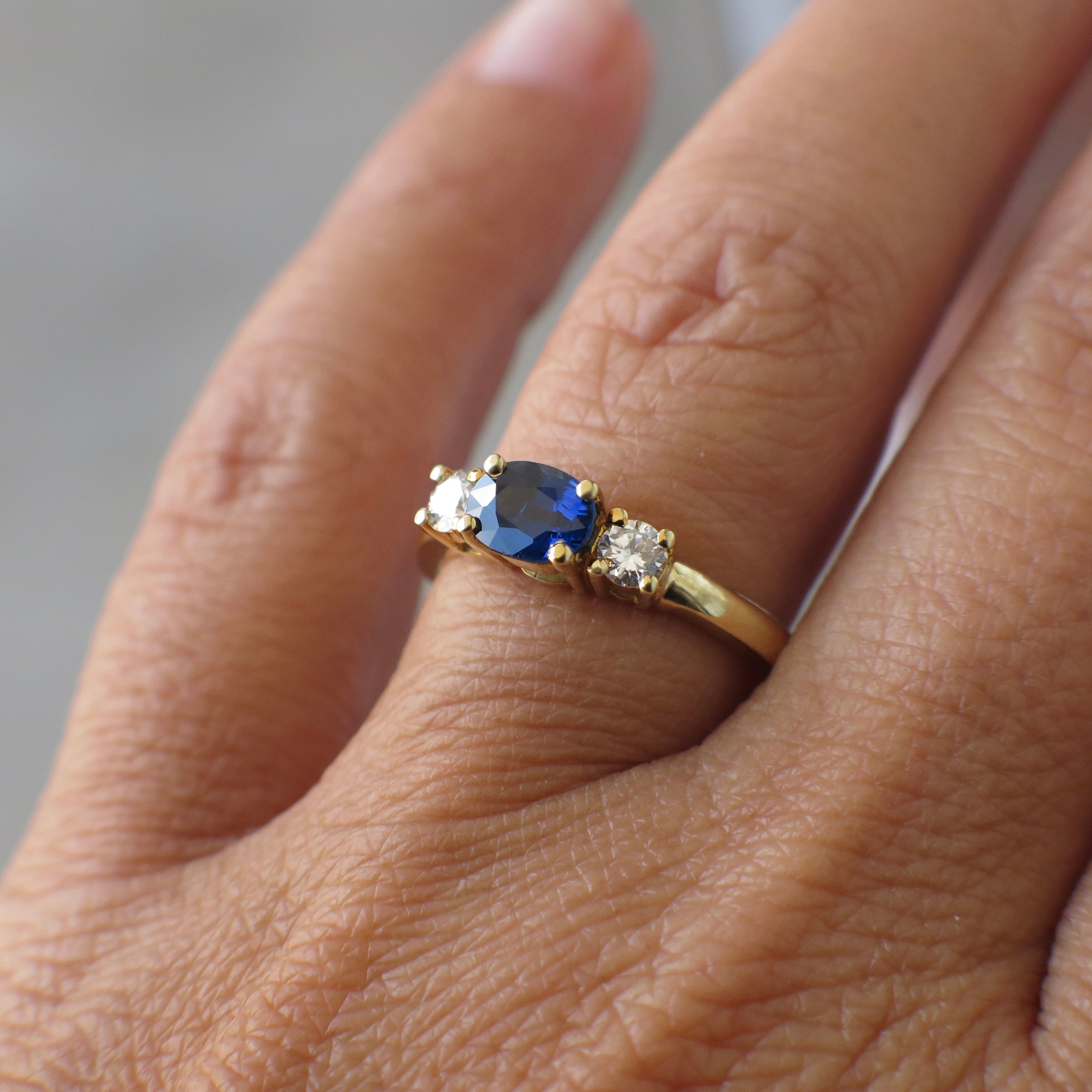 Vintage 18K gold east-west sapphire diamond three-stone ring with elegant design, featuring sparkling gemstones and a gold band.