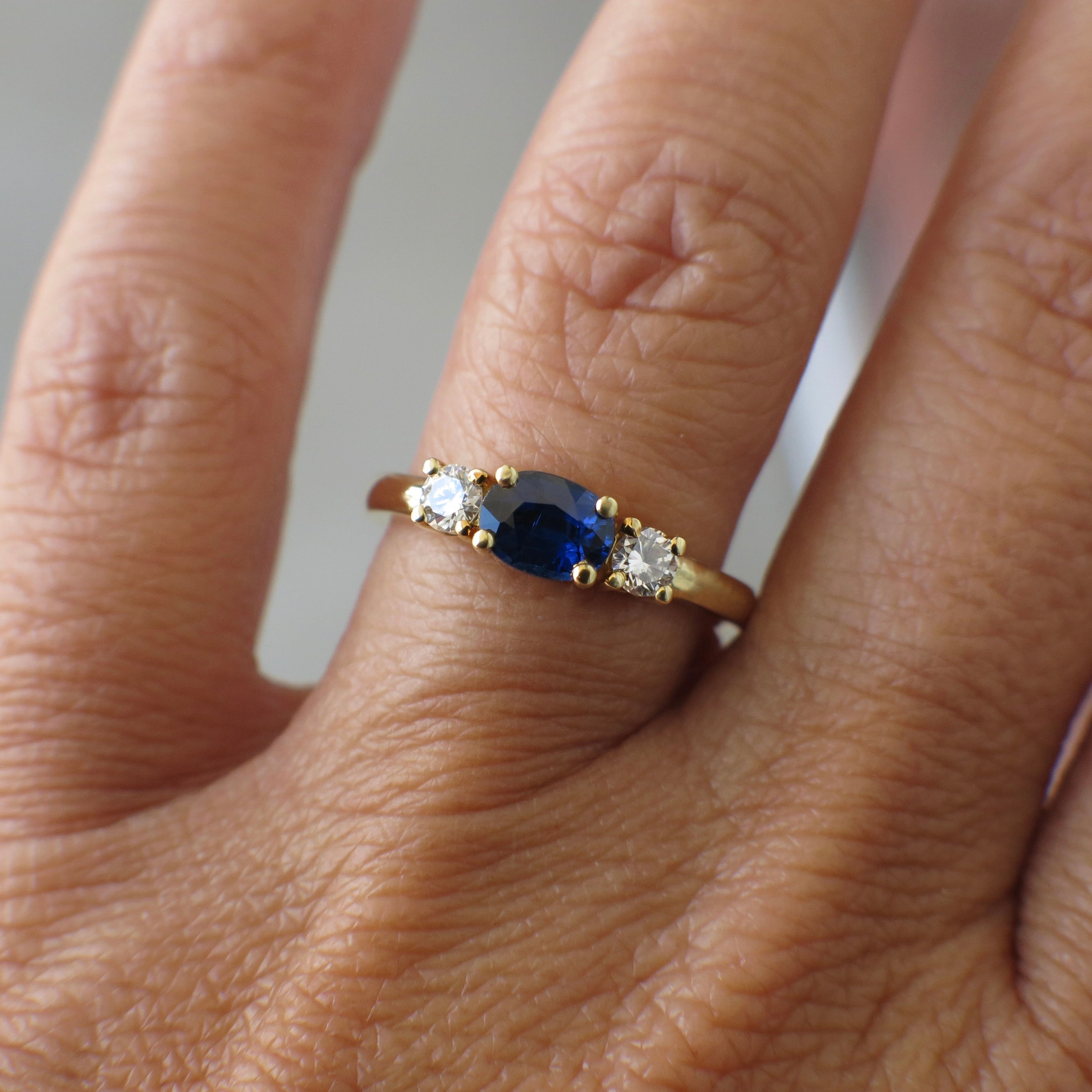 Vintage 18K gold east-west sapphire diamond three-stone ring with intricate detailing, crafted by Black Market LLC.