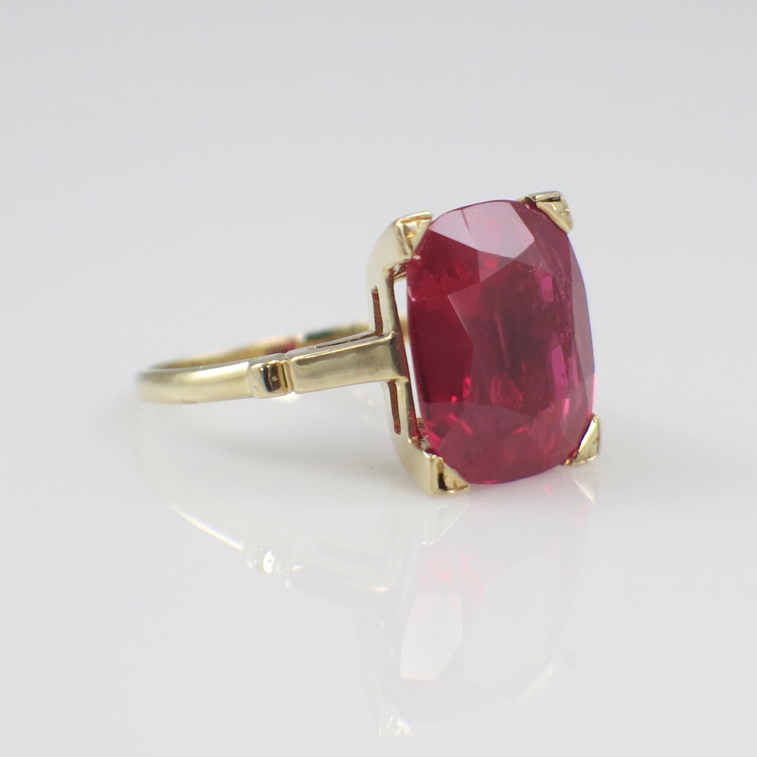 Gold ring with a large red gemstone on a white background