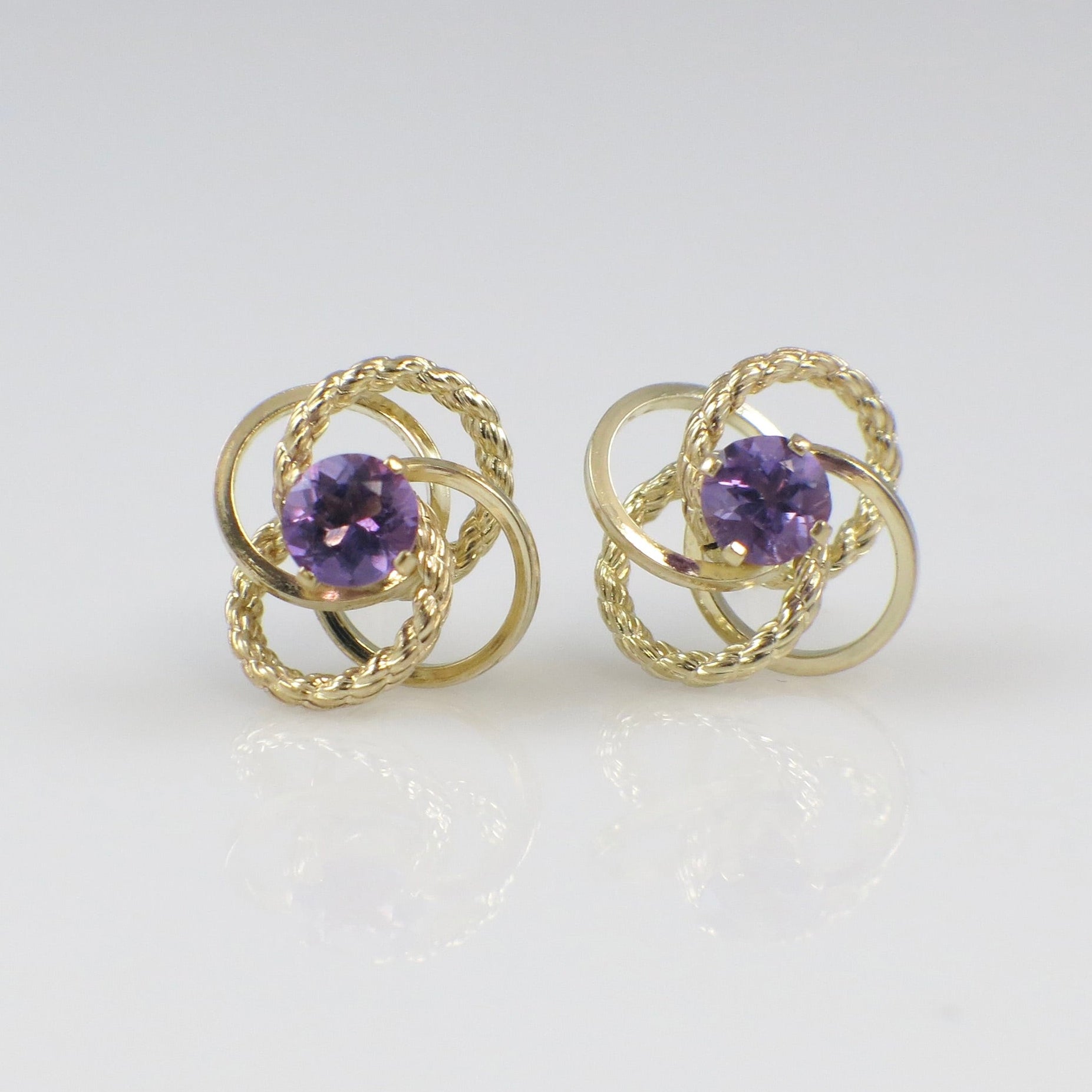 Vintage 14K yellow gold amethyst openwork stud earrings featuring intricate designs and a rich purple gemstone.
