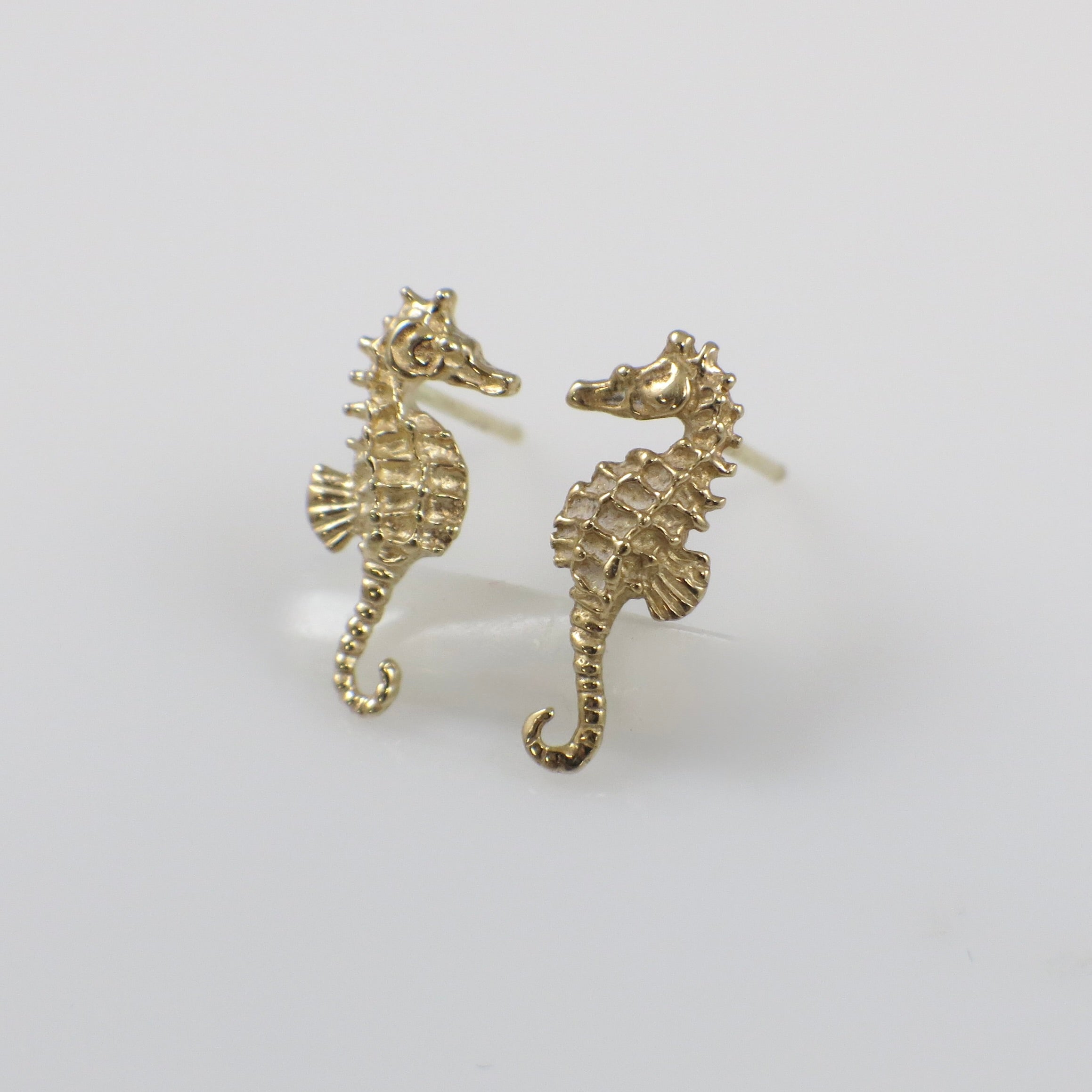 Vintage 14K yellow gold seahorse stud earrings featuring detailed seahorse designs on small gold posts.