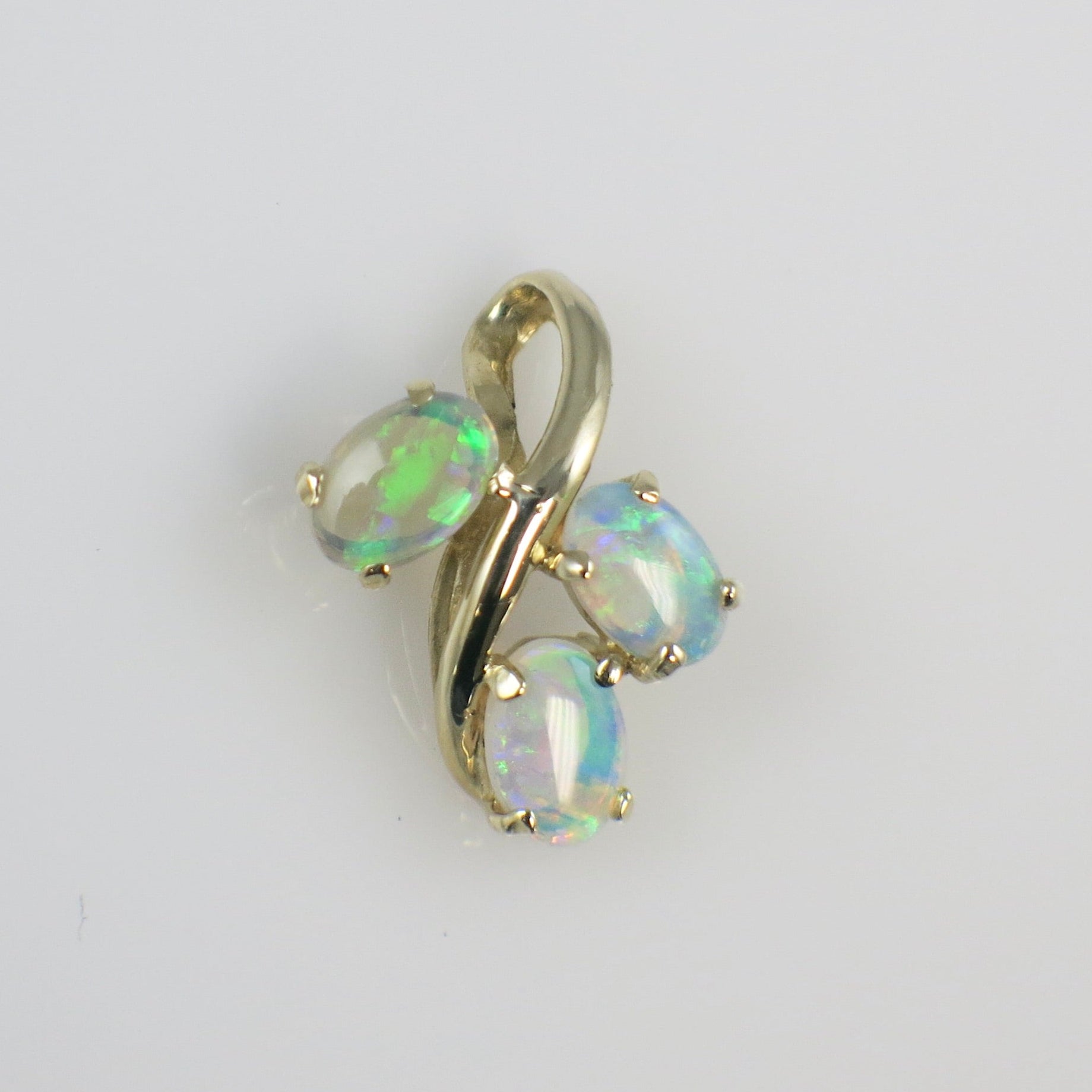 Gold pendant with opal stones on a light gray background