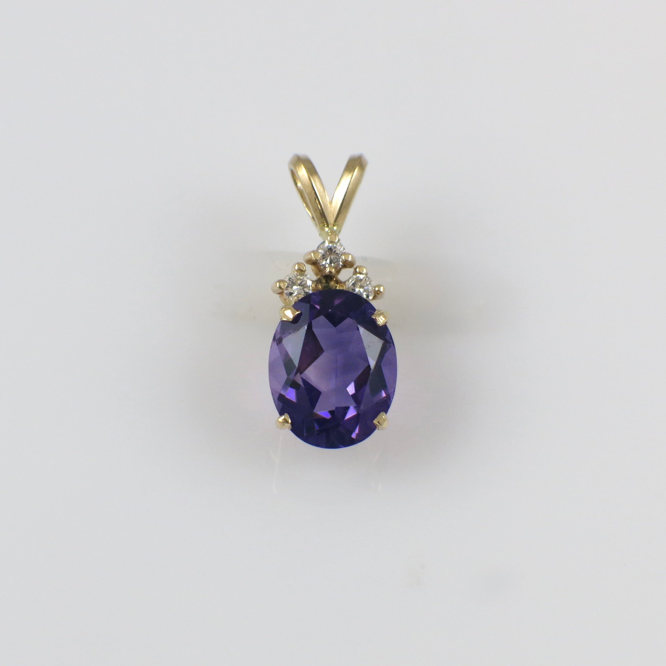 Vintage 14K yellow gold amethyst and diamond pendant necklace with intricate design, featuring a central purple gemstone.