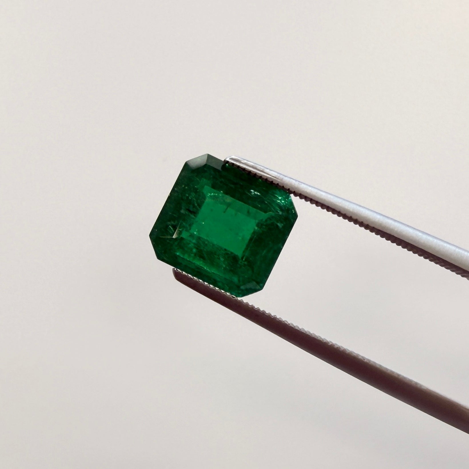 GIA Certified 2.43ct emerald gemstone with octagonal step cut, F1 minor enhancement, showing vibrant green color and precise facets.