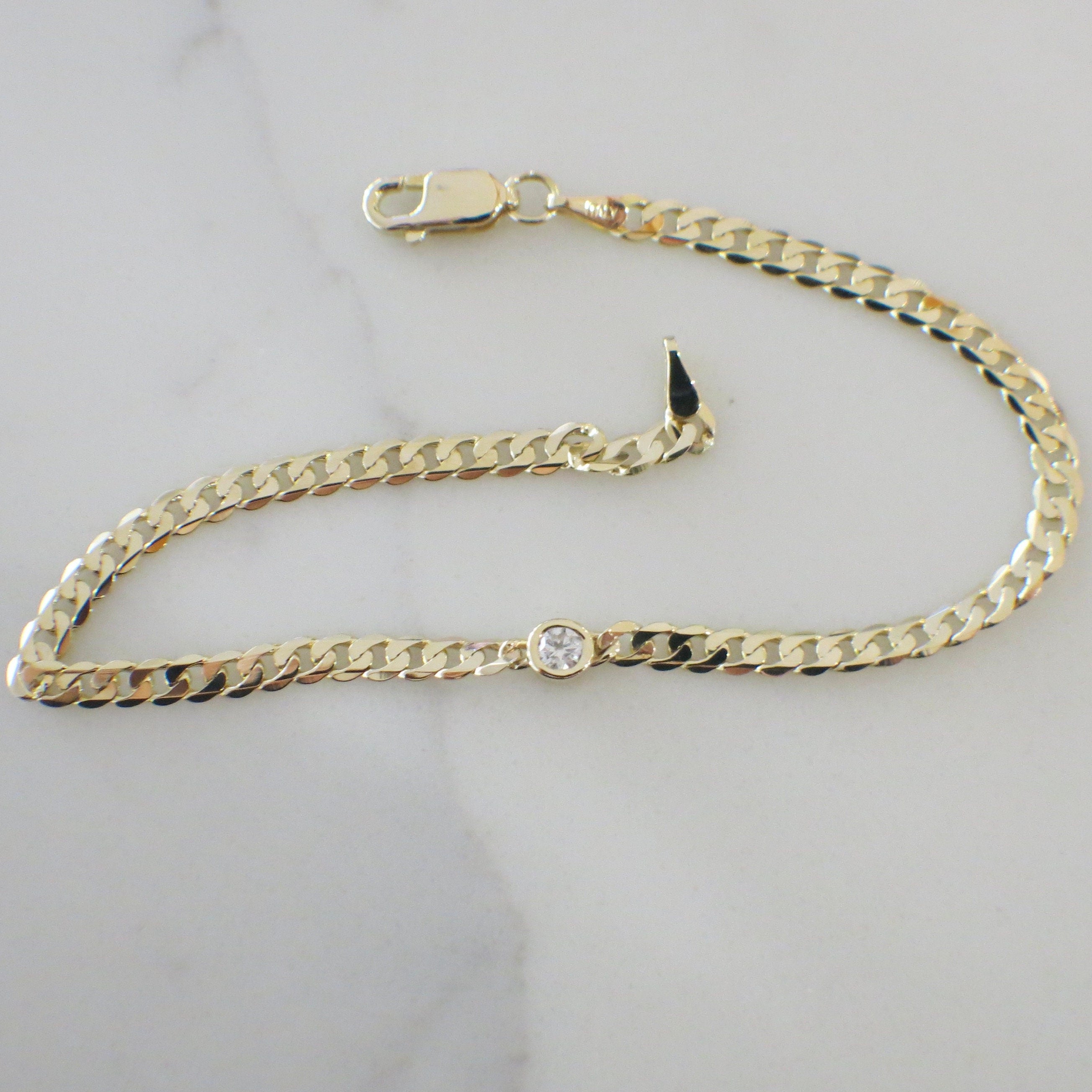 14K yellow gold bezel set diamond curb chain bracelet featuring .10 CT diamonds, 7-inch length, by Black Market LLC.