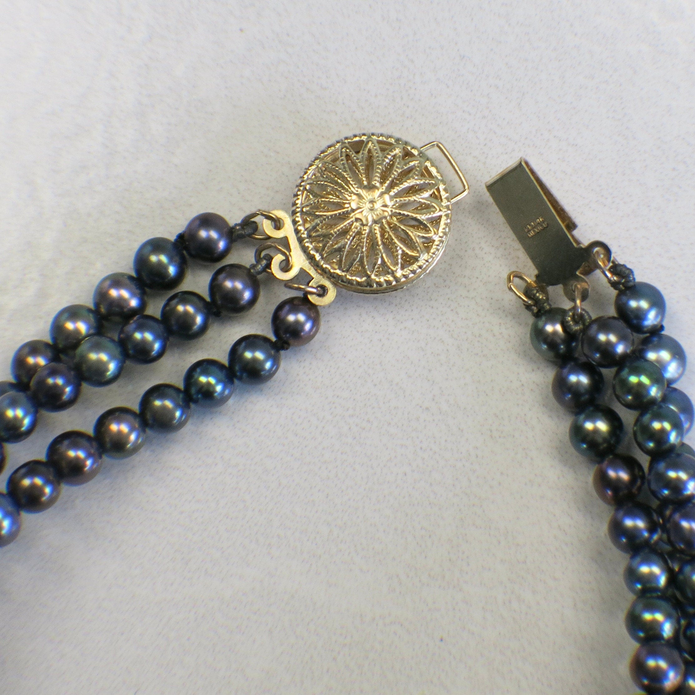 14K yellow gold three-strand Tahitian black pearl bracelet with vintage filigree clasp from Black Market LLC.