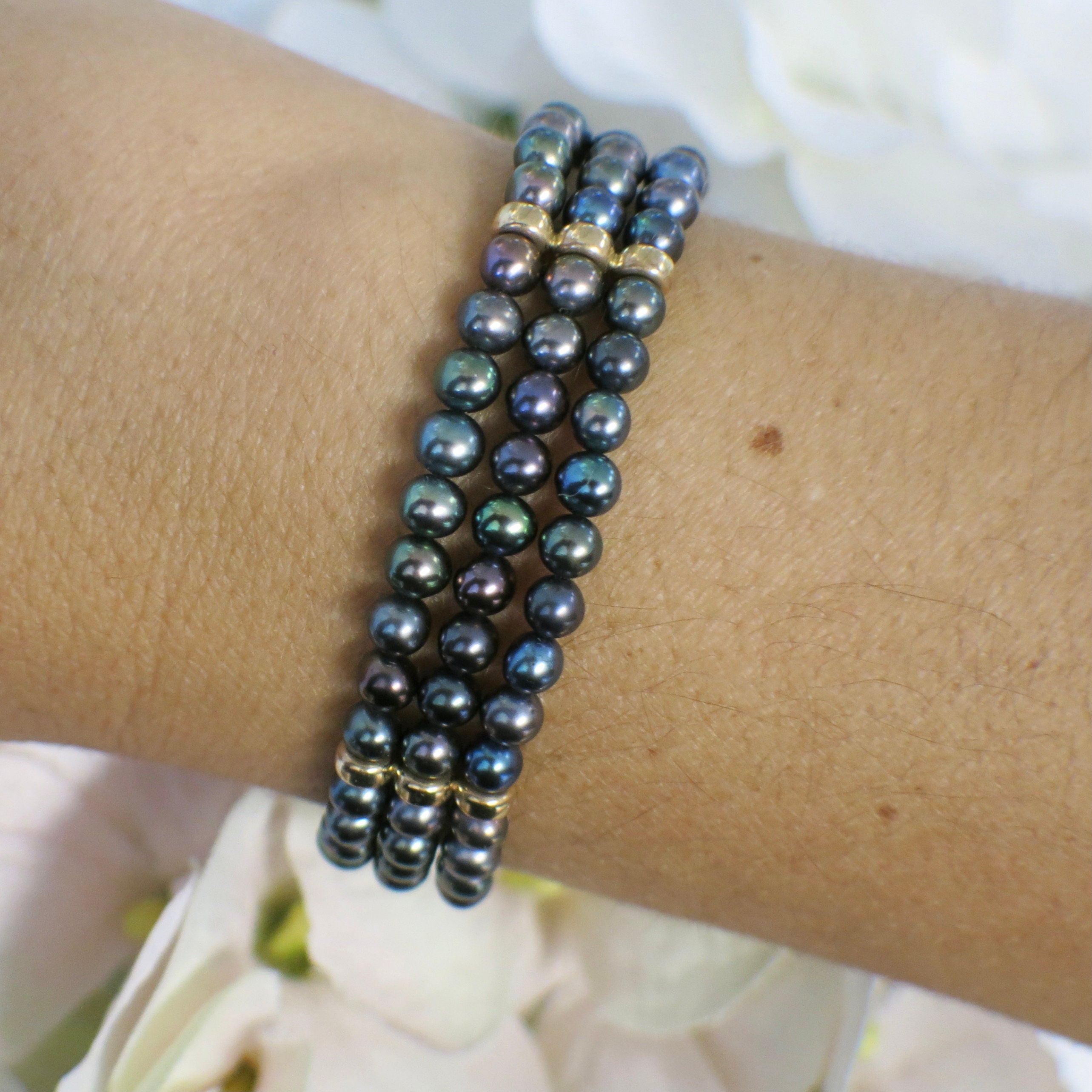 14K yellow gold three-strand Tahitian black pearl bracelet with vintage filigree clasp, elegant and luxurious jewelry piece.