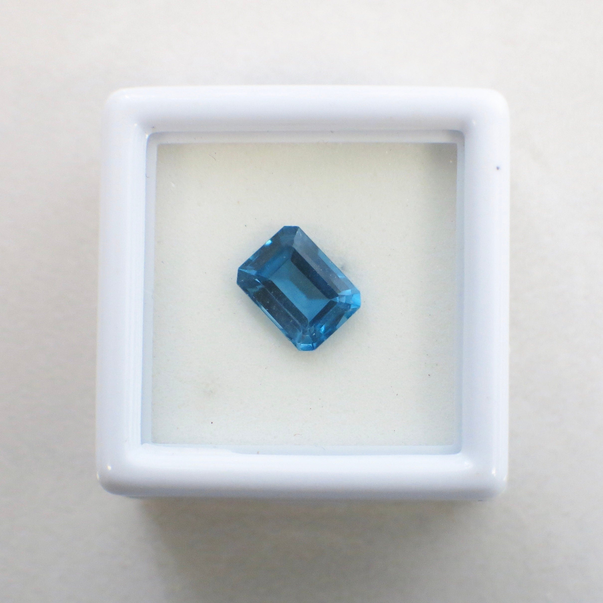 2.08 Carat emerald cut blue topaz loose gemstone, 8x6mm December birthstone, showcasing vibrant blue color and clarity.