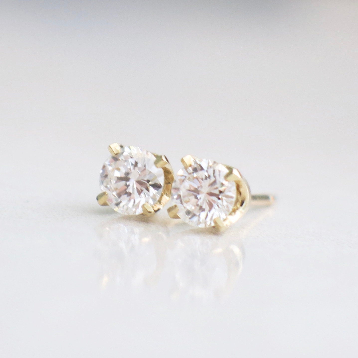 Diamond stud earrings with 0.64 CTW round brilliant diamonds set in 14K yellow gold with threaded backs.
