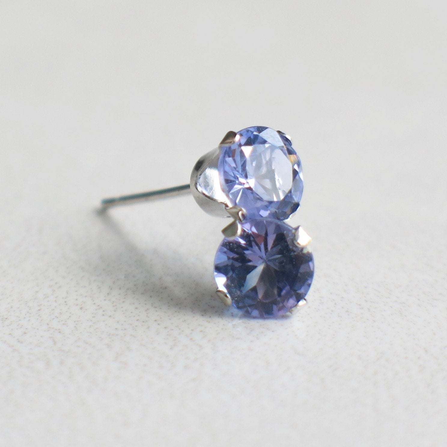 Tanzanite stud earrings in 14K white gold with 5 mm round gemstones, featuring a simple and elegant design.