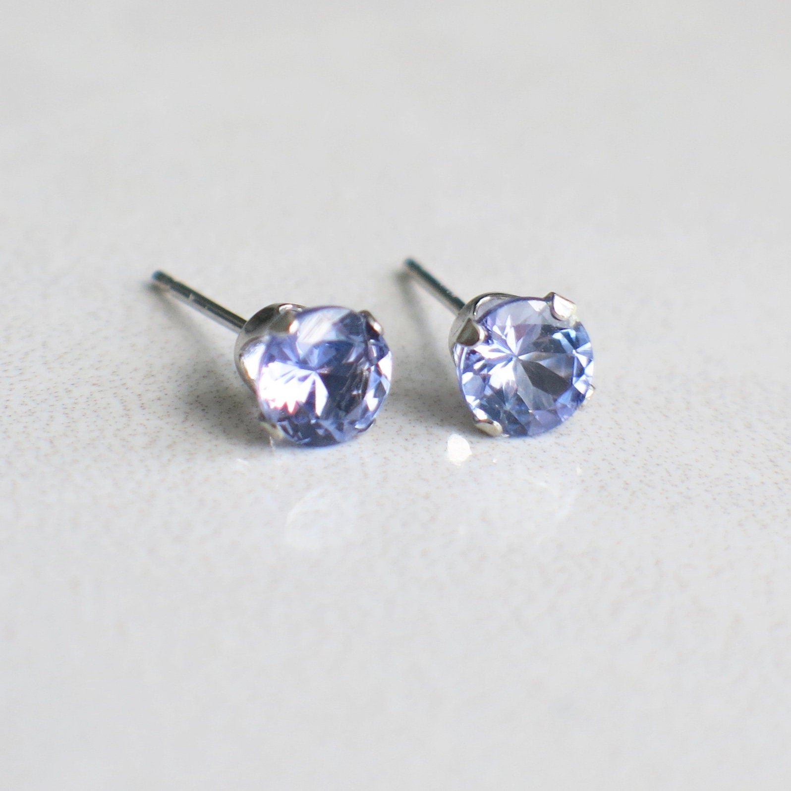Tanzanite stud earrings in 14K white gold with 5mm round gemstones, elegantly designed by Black Market LLC.