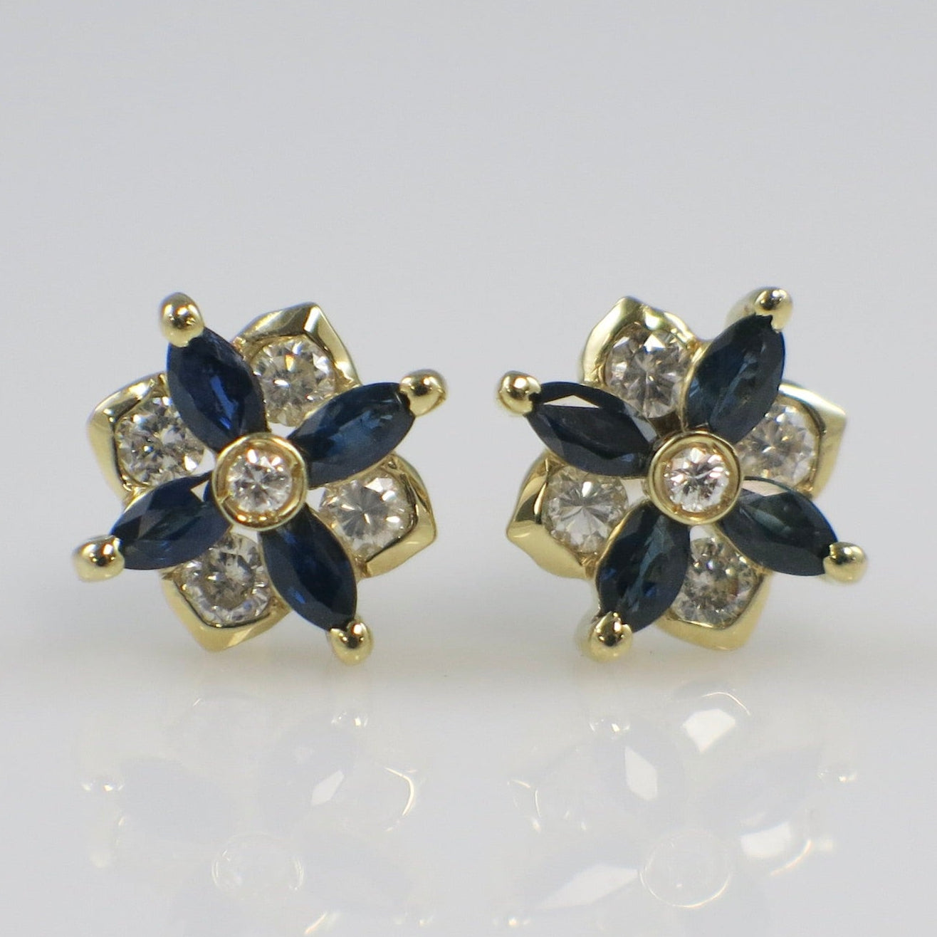 Pair of gold earrings with blue gemstones on a light gray background