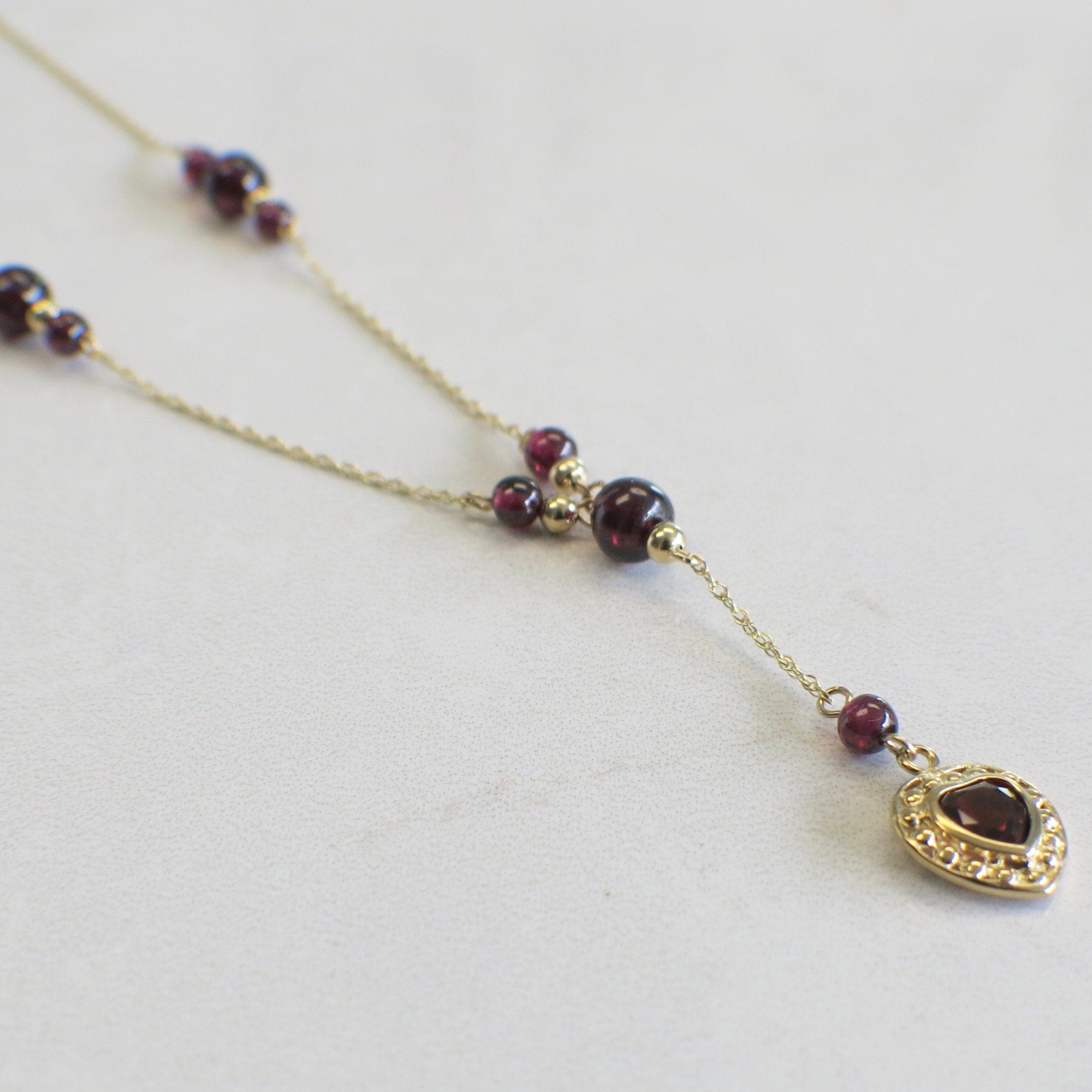 14K gold garnet bead drop necklace with heart charm, featuring rhodolite garnet dangle and delicate chain.