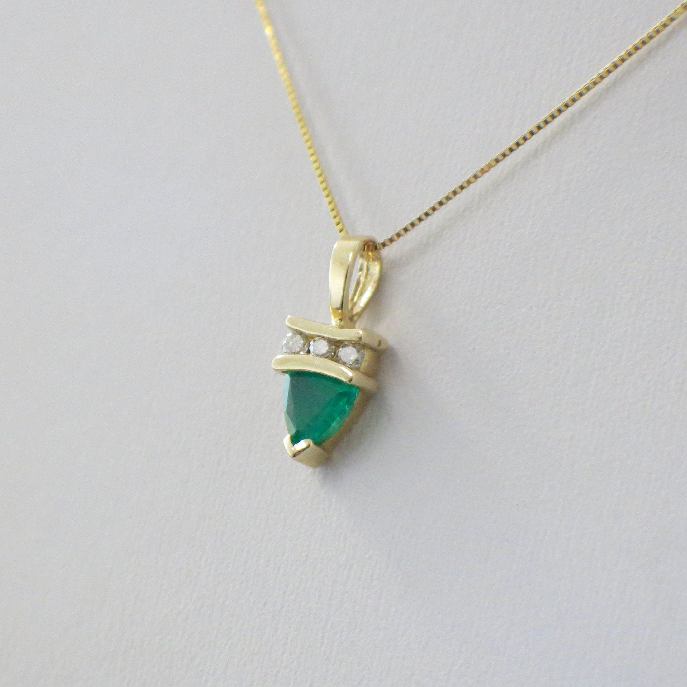 14K yellow gold necklace with a trillion emerald and diamond pendant on box chain, featuring elegant jewelry design.